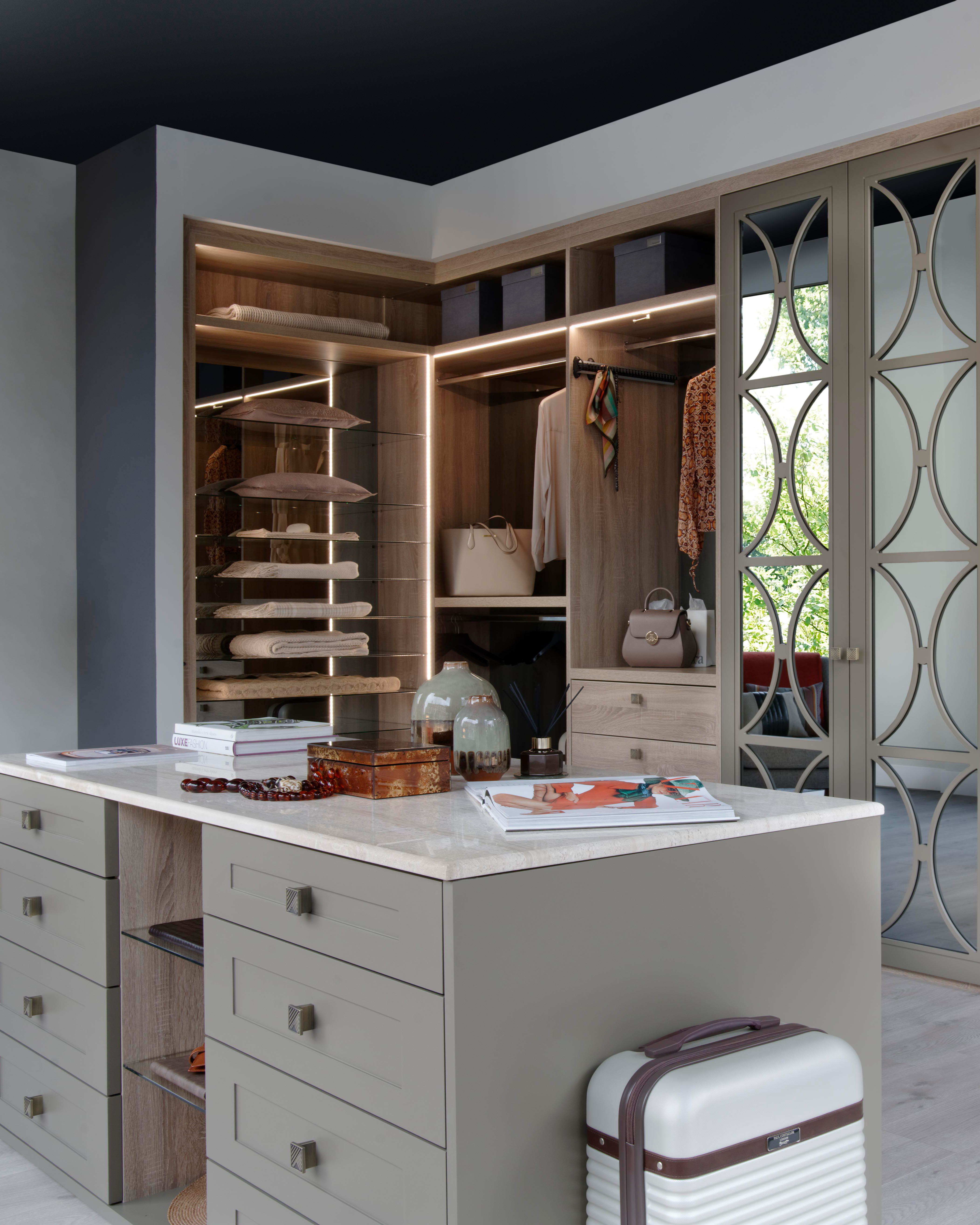 modern luxury dressing room with a central island and built in wardrobes behind it with LED lights, displaying bags and shoes