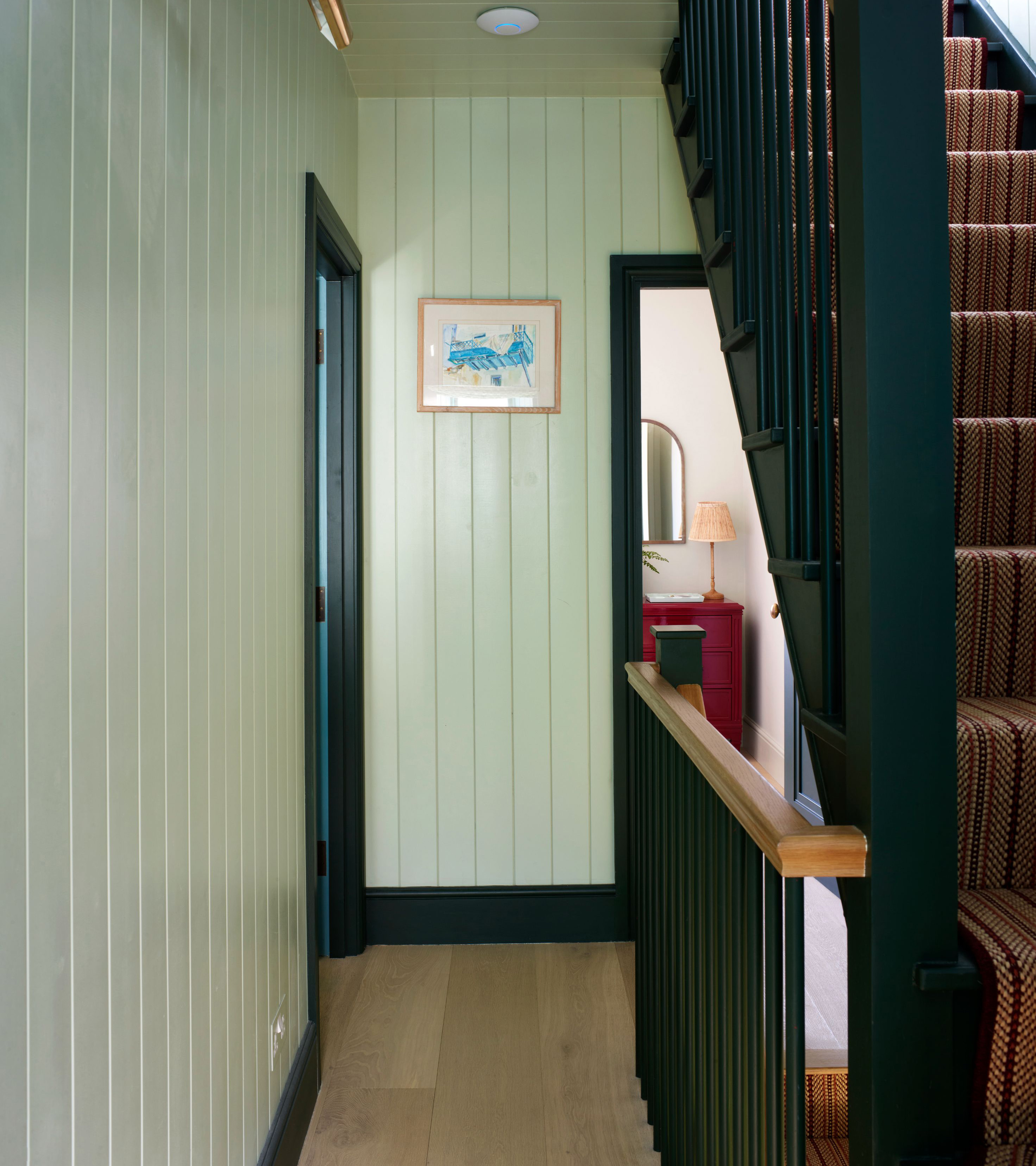 a hallway with sage green panelled walls