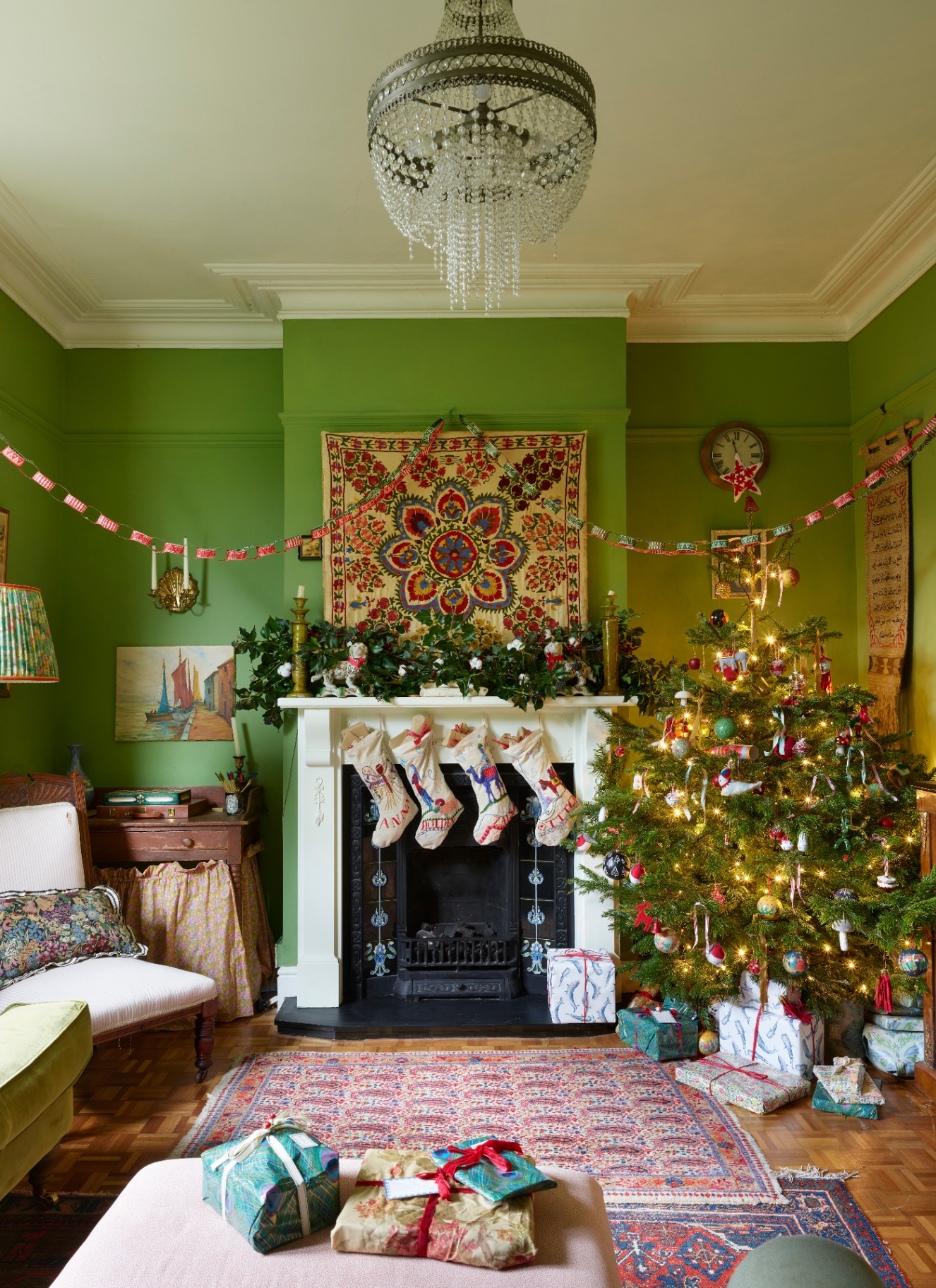 An apple-green sitting room featuring personalized embroidered stockings hanging from the mantelpiece and a bright Christmas tree