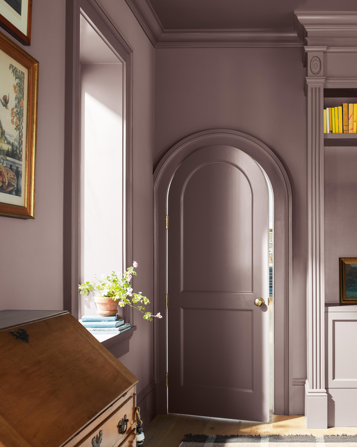a purple colour drenched hallway with an arched door