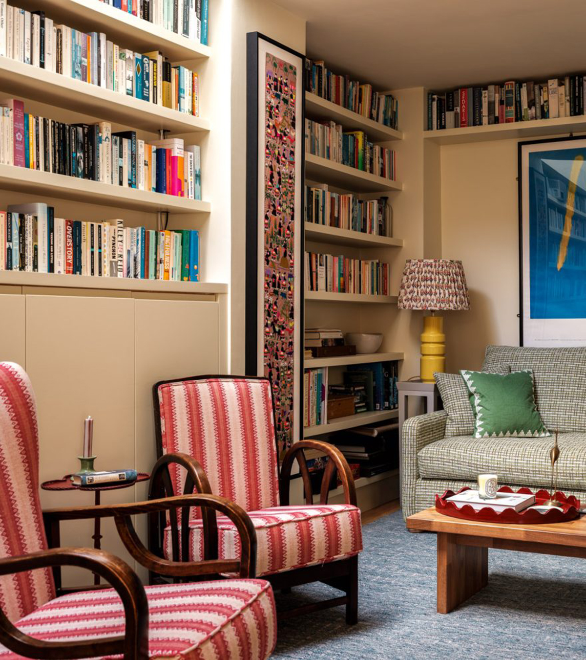 a living room with colourful chairs and bookcase