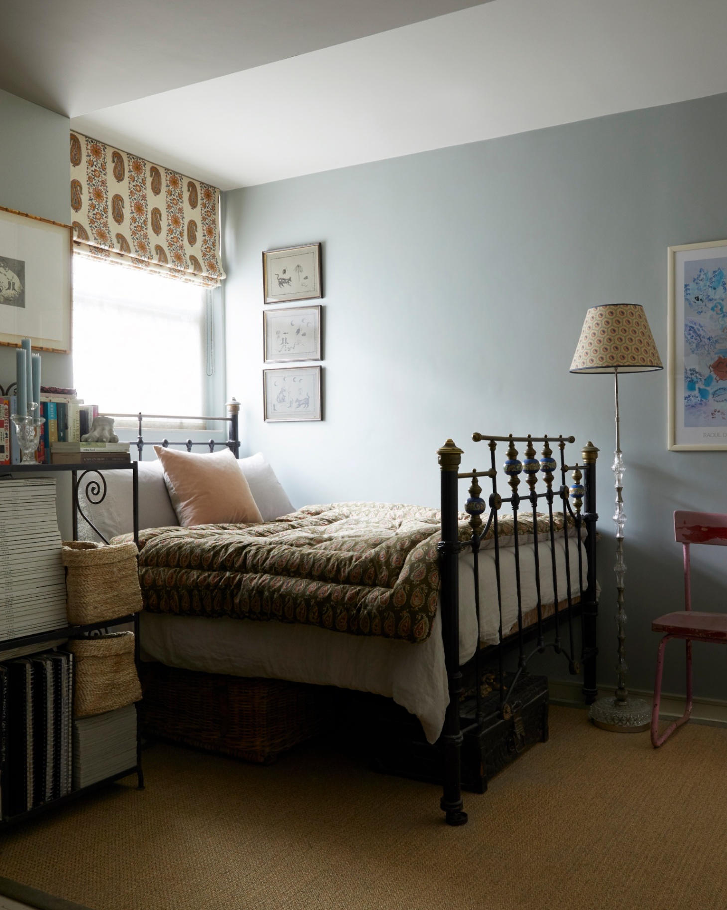 a bedroom with a pale blue walls, a wrought iron bed with an olive green patterned bed spread and a jute rug on the floor