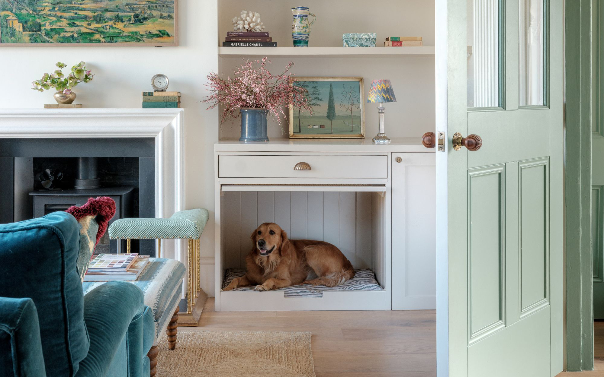 a golden retriever in a built in dog nook in a living room with white alcove shelving, a woodburner fireplace and a teal sofa