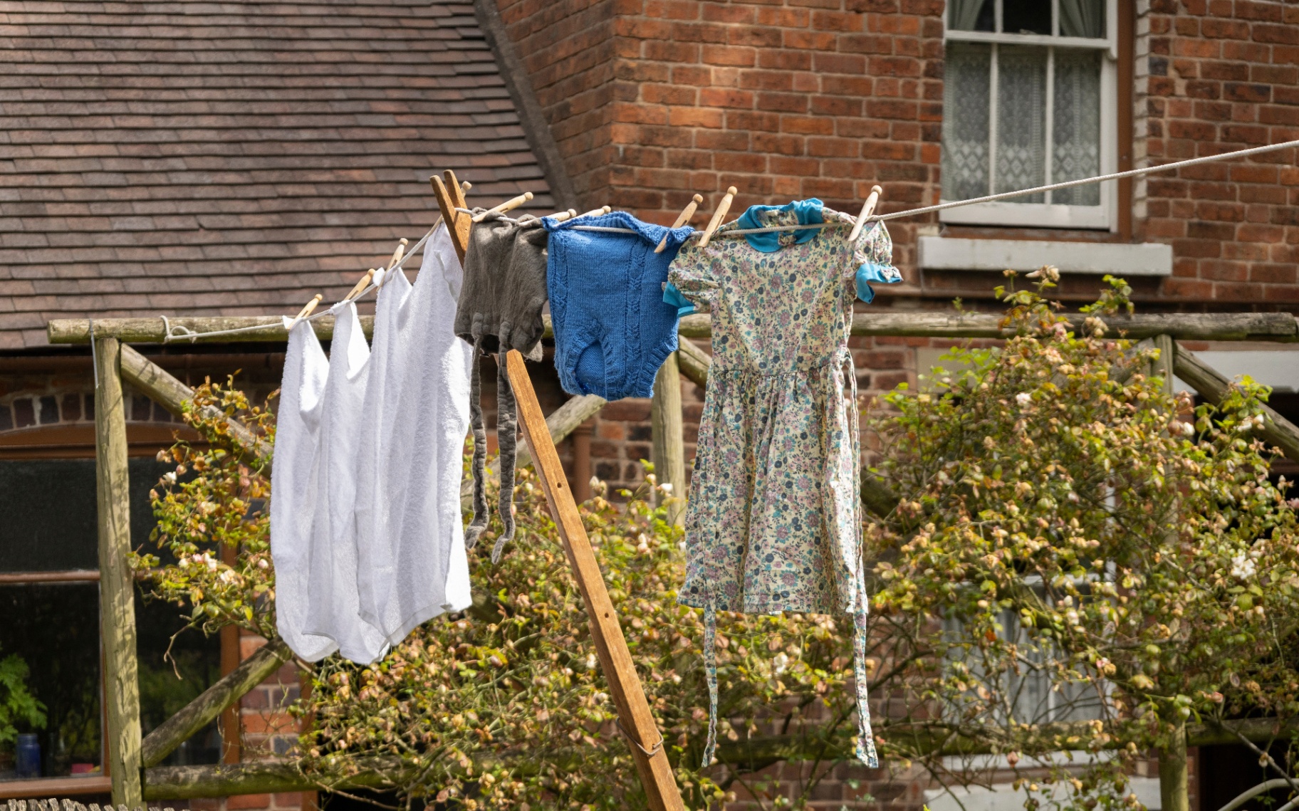 clothes drying on an outdoor clothes line infront of a red brick house