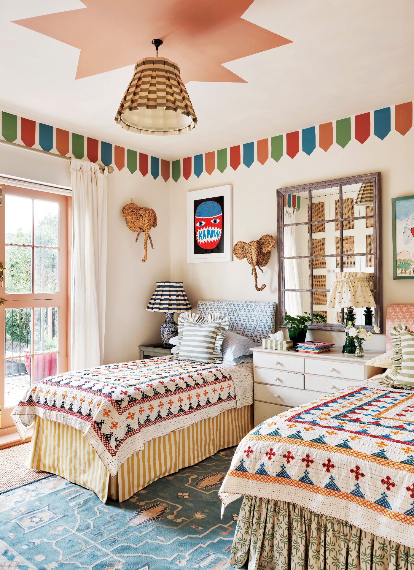 a childrens bedroom with white walls and ceiling with a terracotta star painted on the ceiling where the light is and two single beds with patterned bedding
