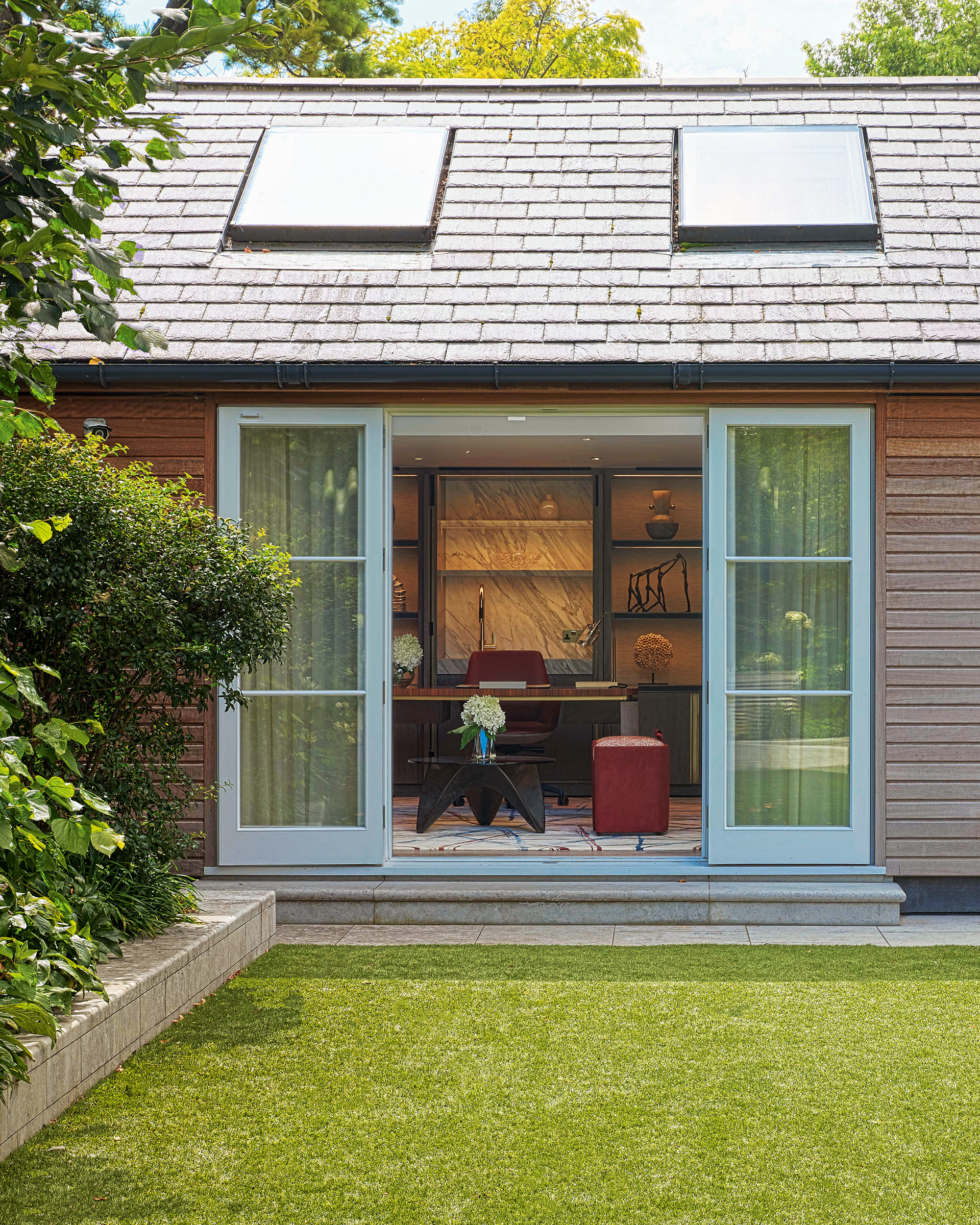 a garden room with sky lights and open pale blue doors looking into a room with a dining table