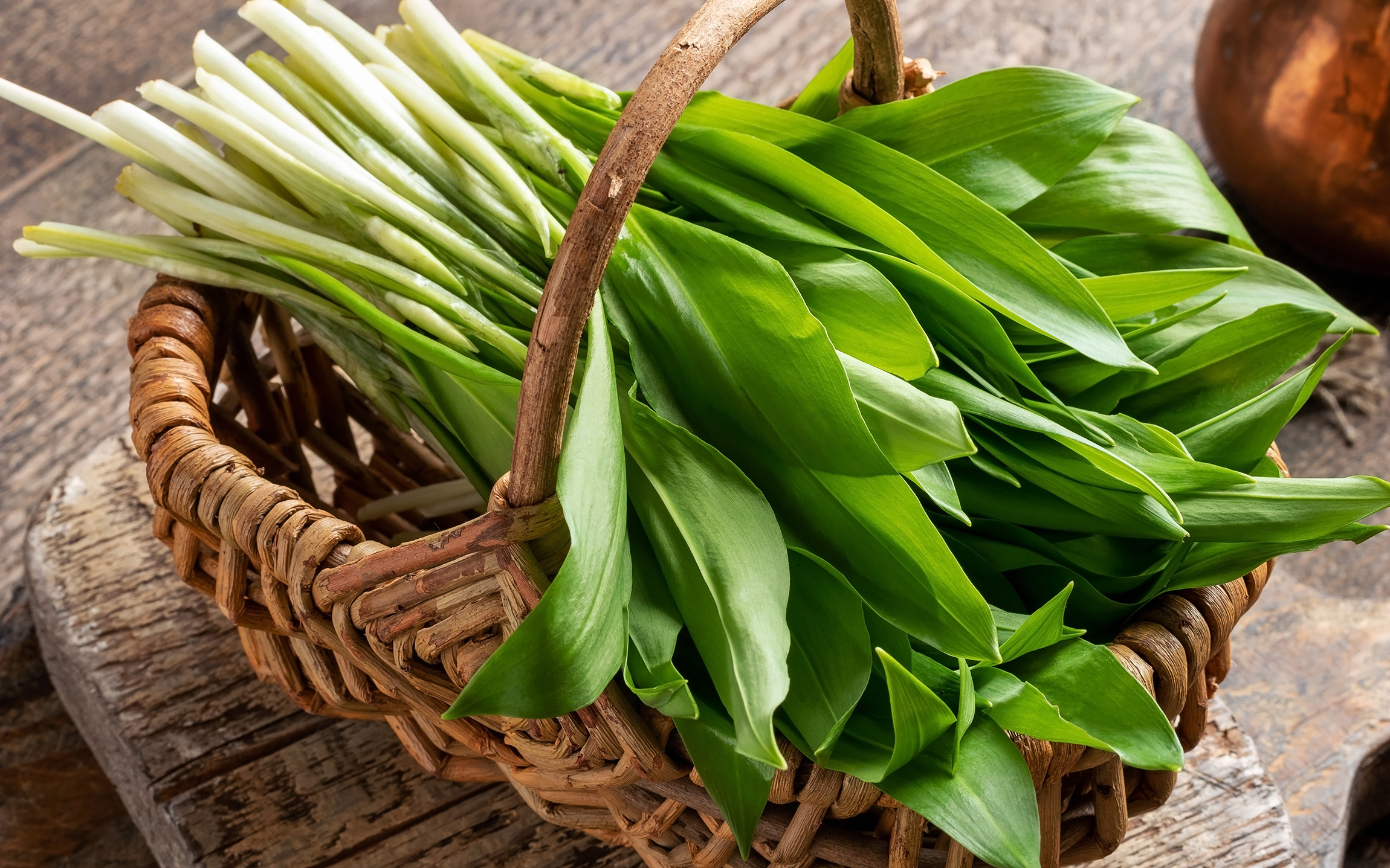 a bunch of wild garlic in a wicker basket with a handle