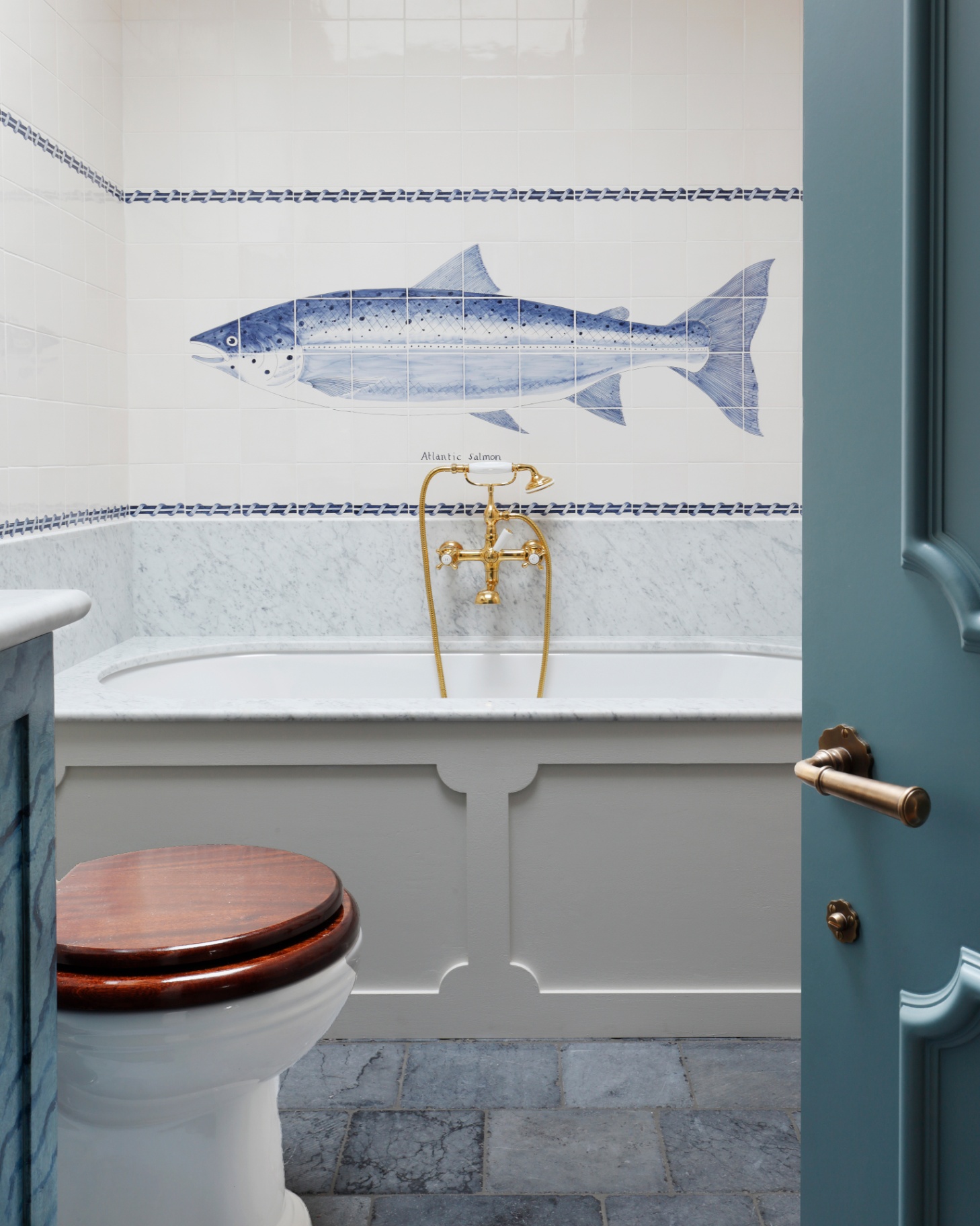 a bathroom with white and blue tiles with a large fish motif and a blue open door