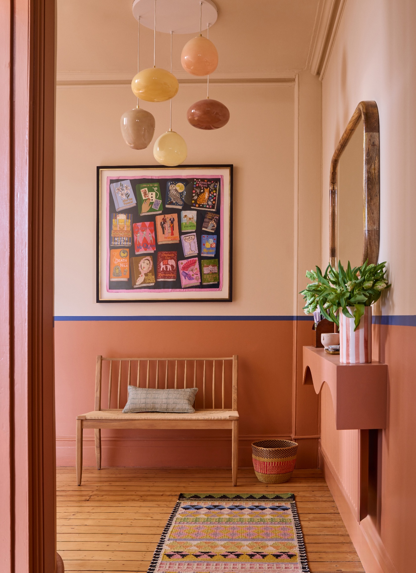 a hallway with peach pink walls and a multi height glass orb pendant light