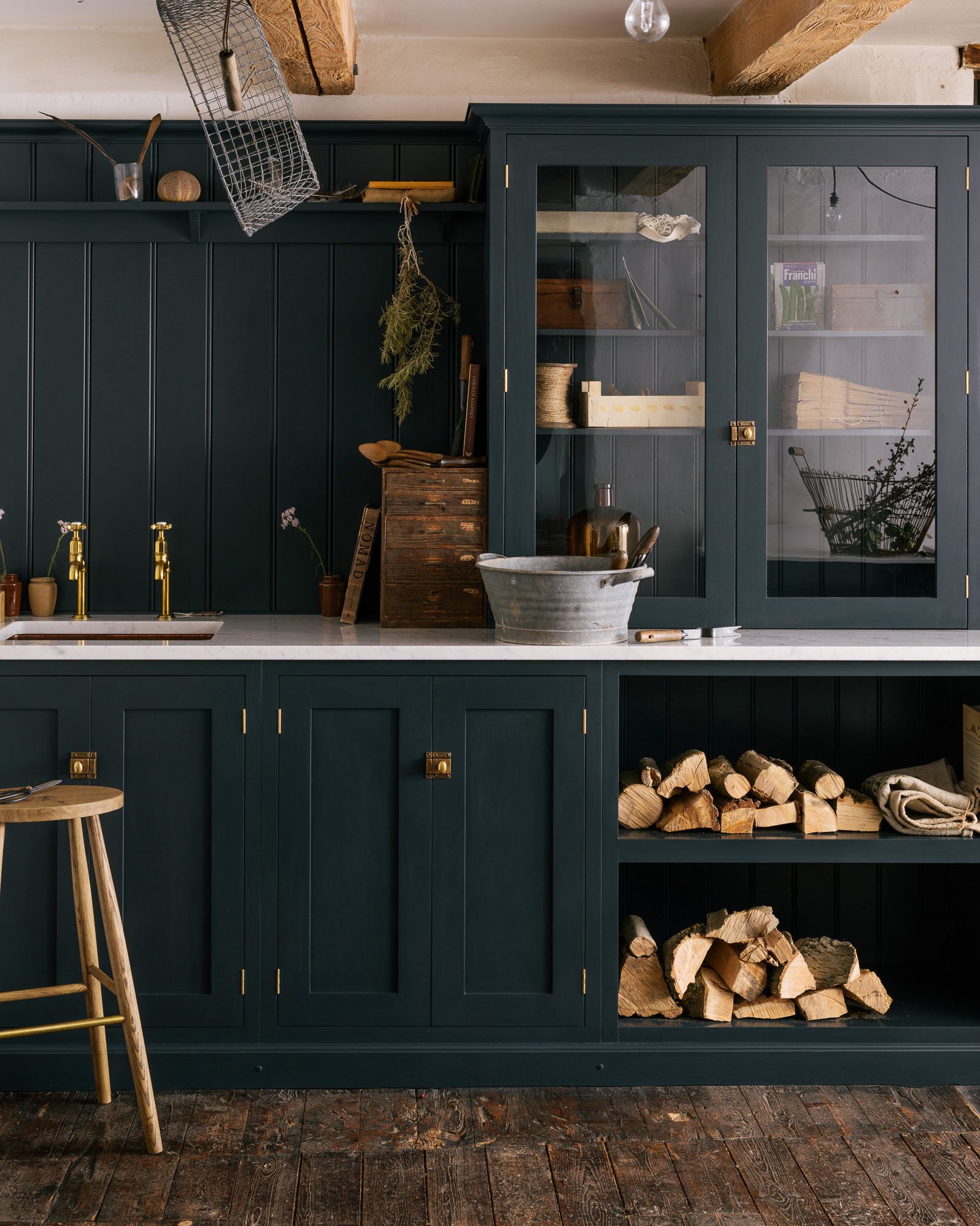 a dark navy utility room with gold hardware, open shelving with firewood