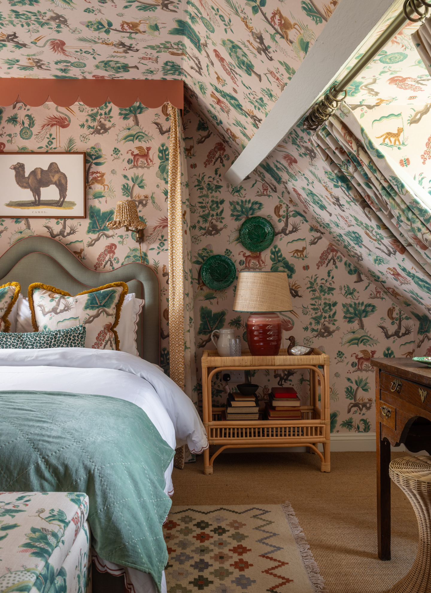 a bedroom with an animal and tree themed storybook wallpaper on the walls and ceilings and a large bed with a canopy and a framed camel print above the headboard