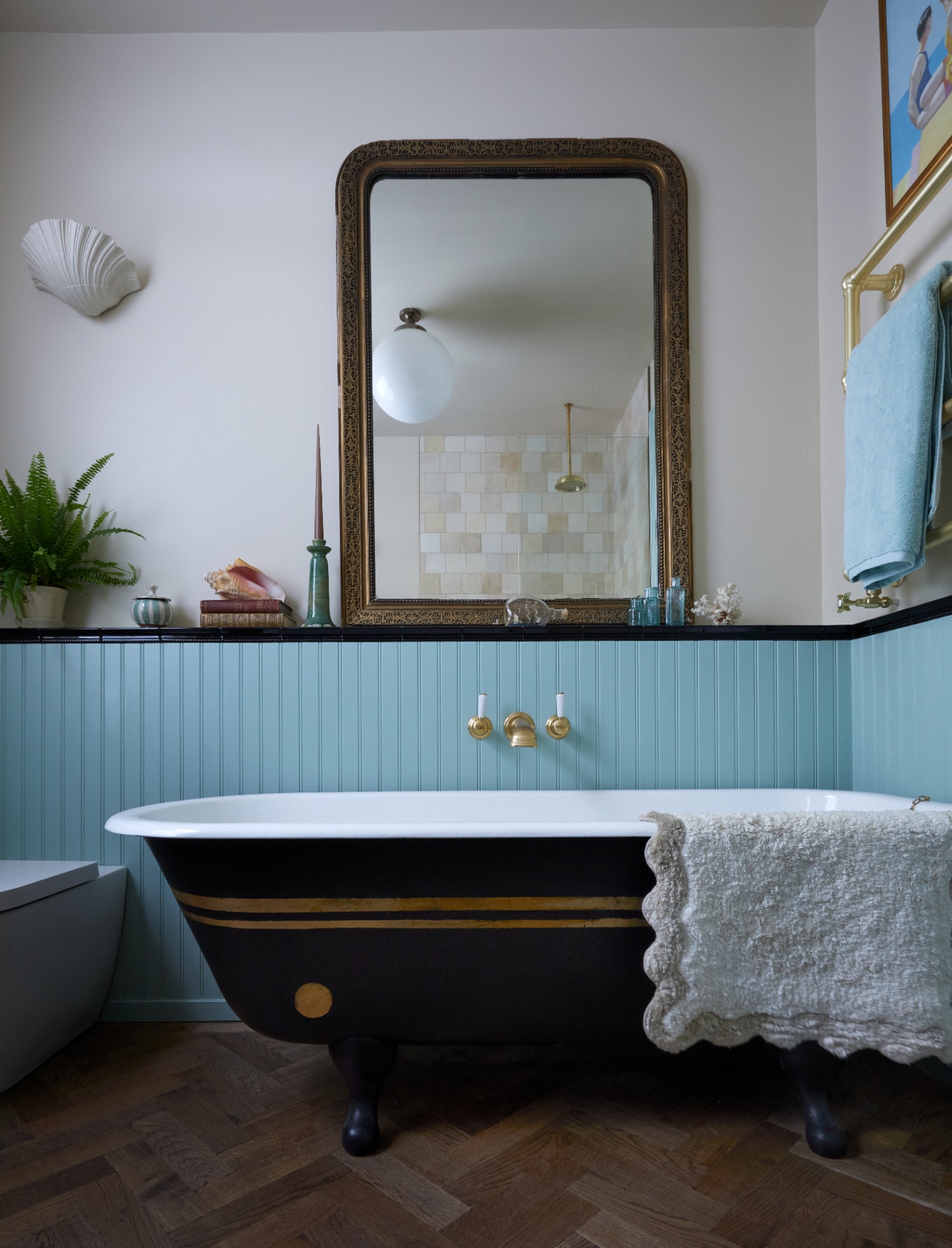 a bathroom pictured with a roll top bath as the focal point, tarnished gold fixtures can be seen, alongside a large antique looking mirror
