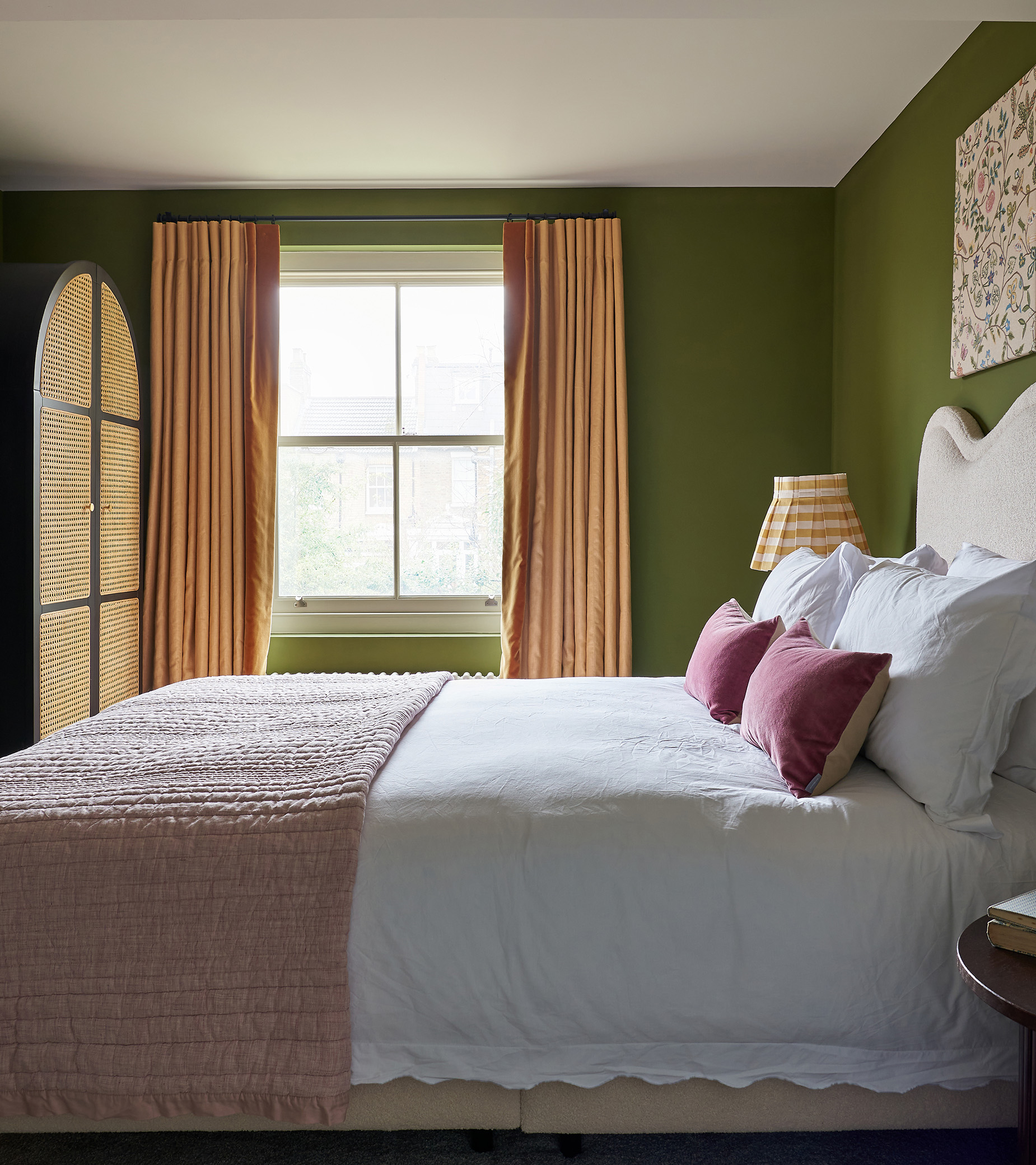 an bedroom with olive green walls, a window with yellow curtains and a bed with a white headboard, white bed linen and a pink bed spread