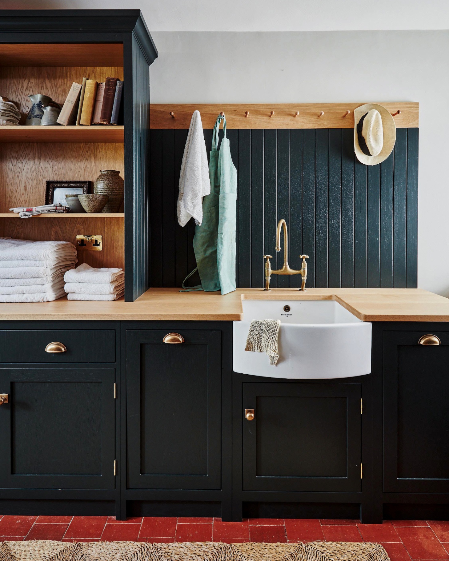 a utility room with dark navy cabinets, a belfast sink and wooden shelves
