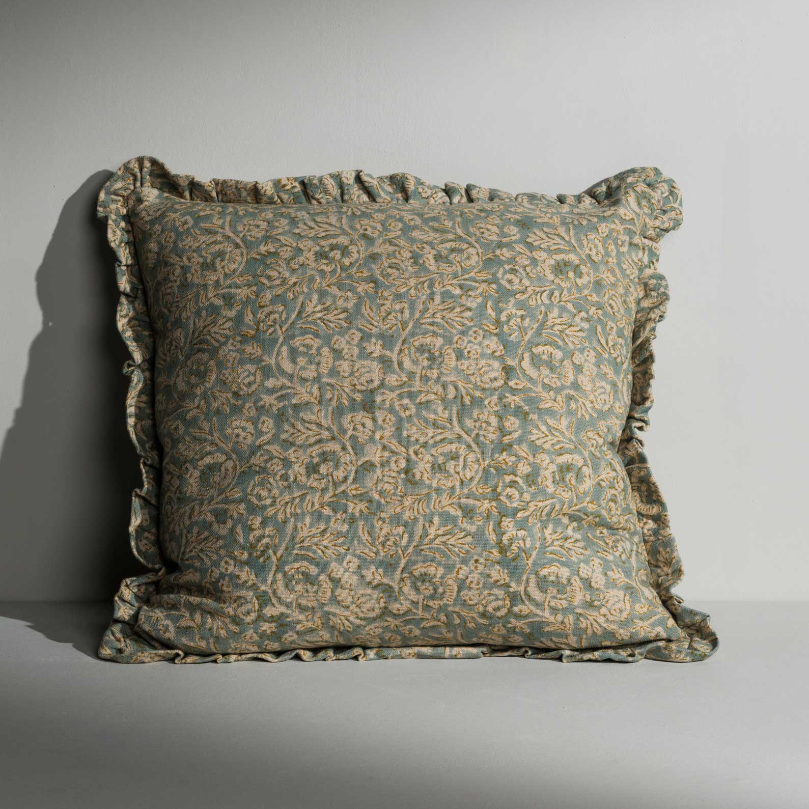 a green floral cushion with ruffle edges