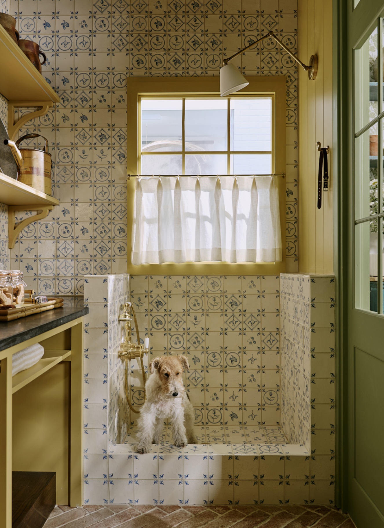 a utility room with a built in dog shower in white and blue delft tiles with a white long haired terrier inside