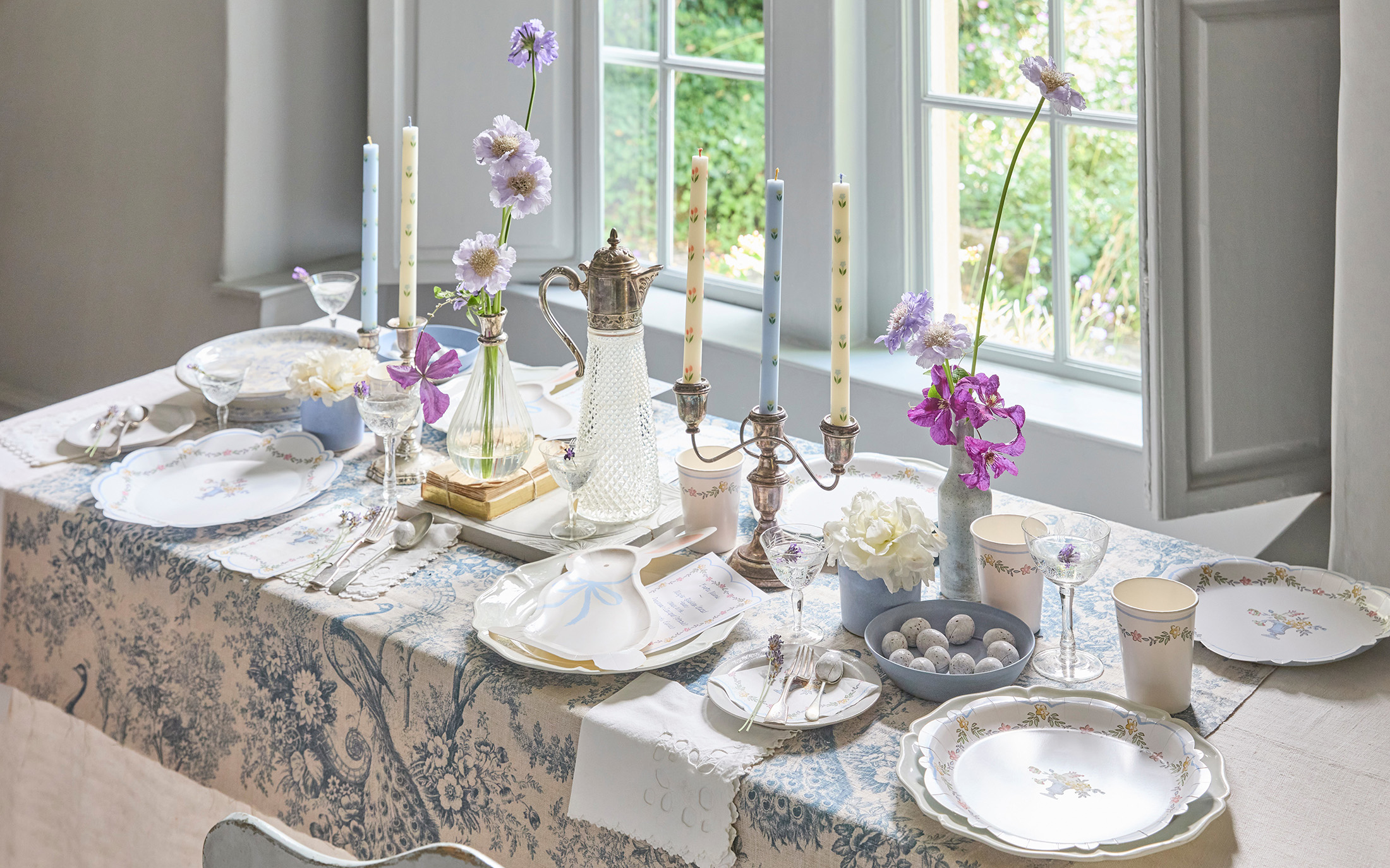 a blue easter table with candle sticks and flowers