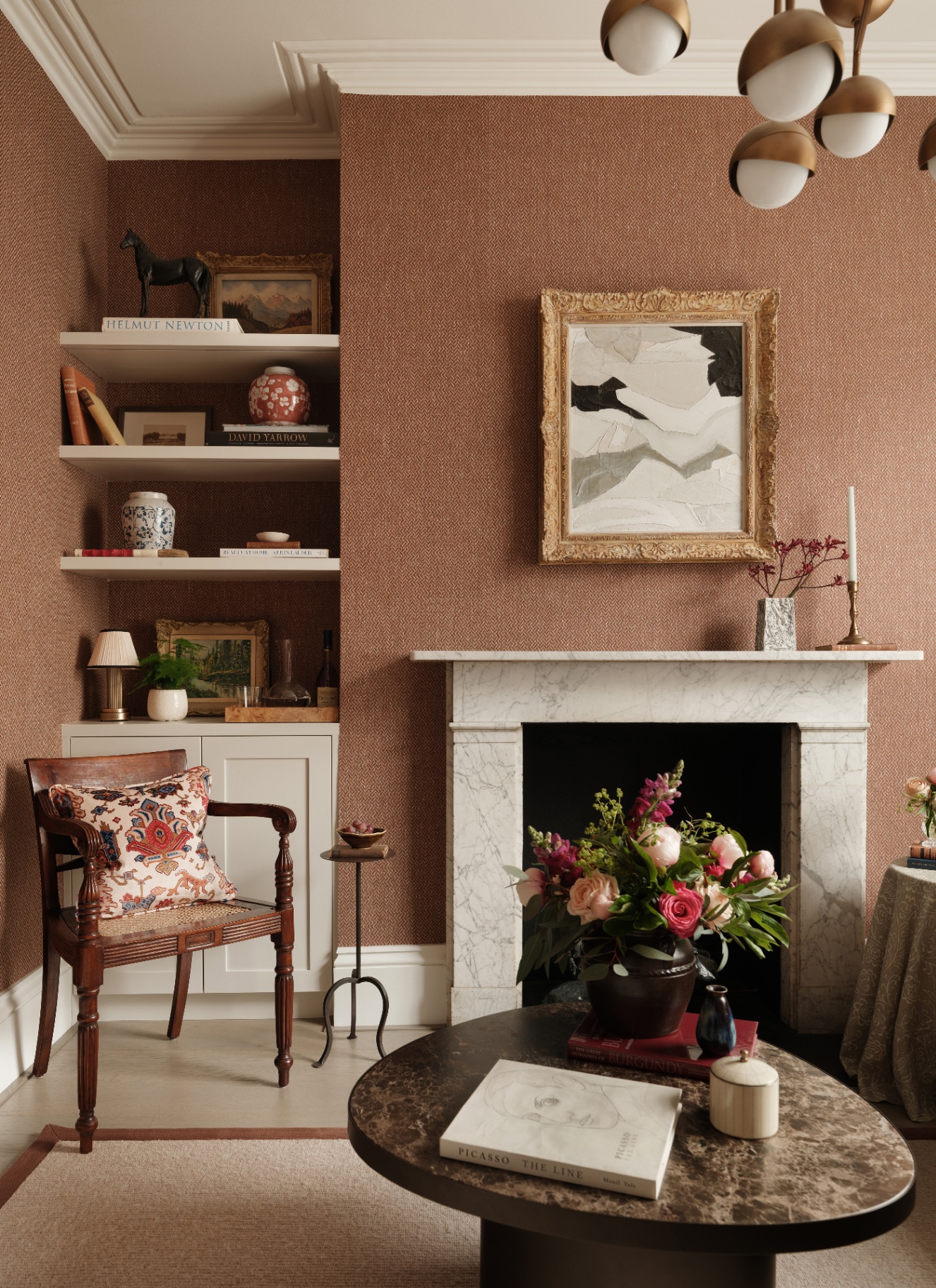 a living room with terracotta textured wallpaper and a large white marble fireplace