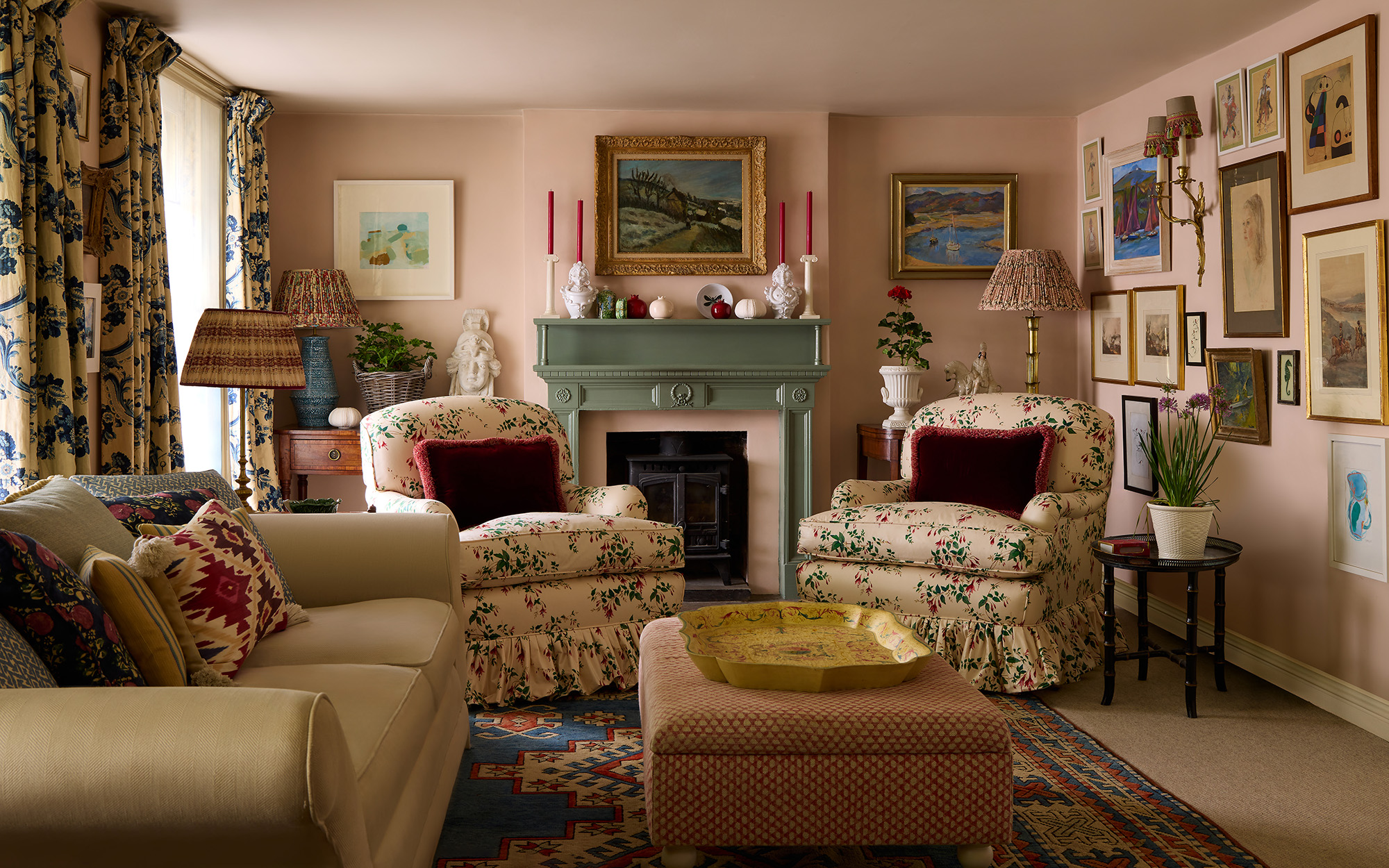 A traditional interior with pink walls, ruffled skirt armchairs and pictures on the wall
