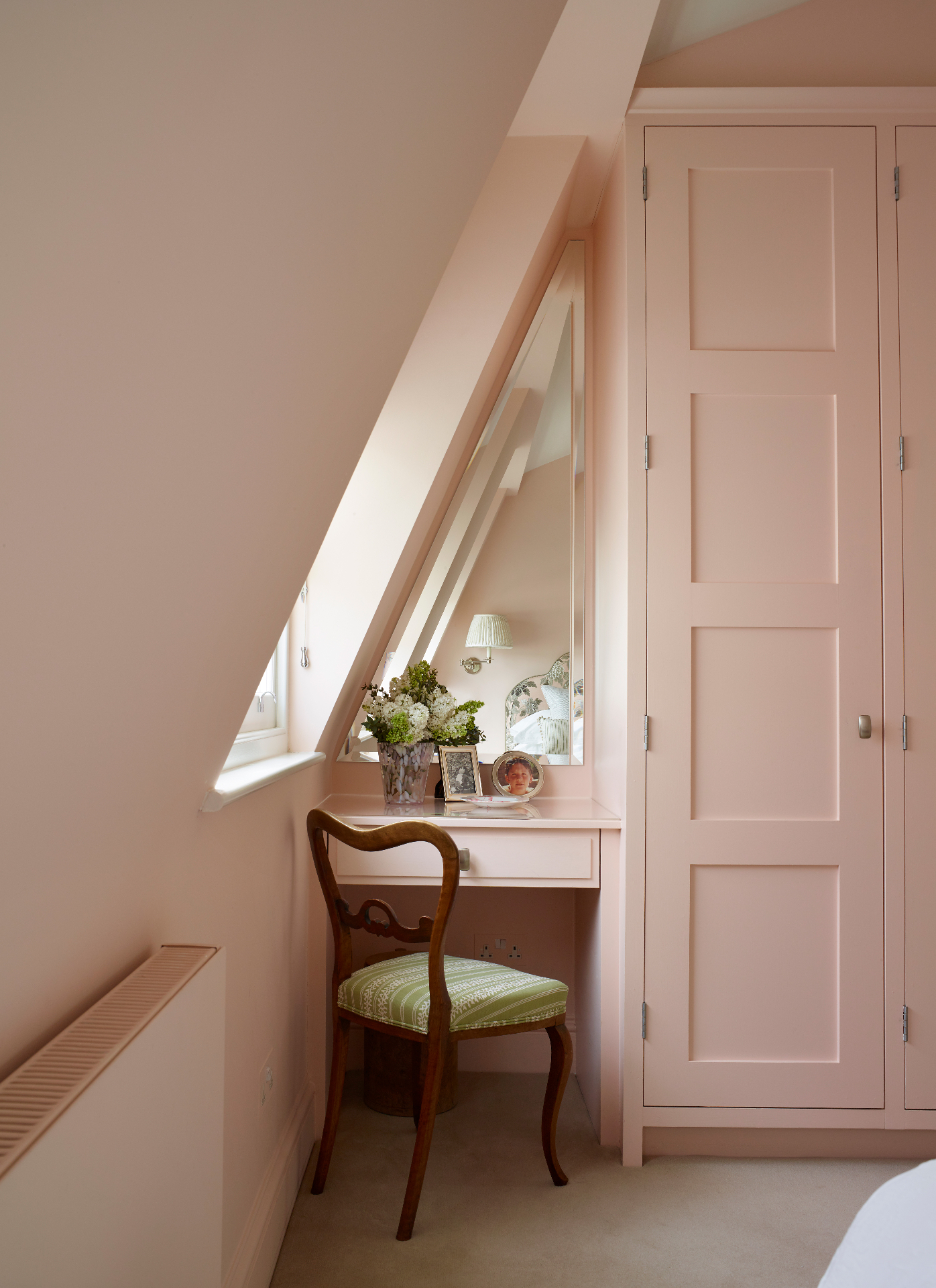 a bedroom corner colour drenched in pale pink with a dressing table nook