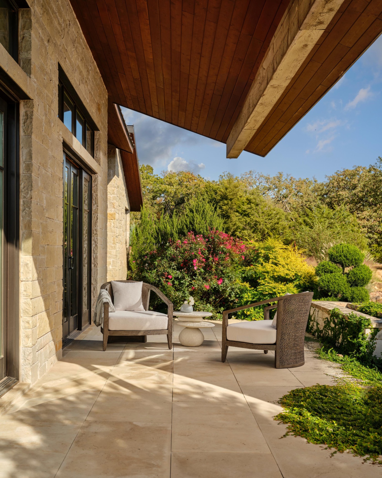 an outdoor patio area with a large wooden awning and a 2 seater dining set with a sculptural coffee table