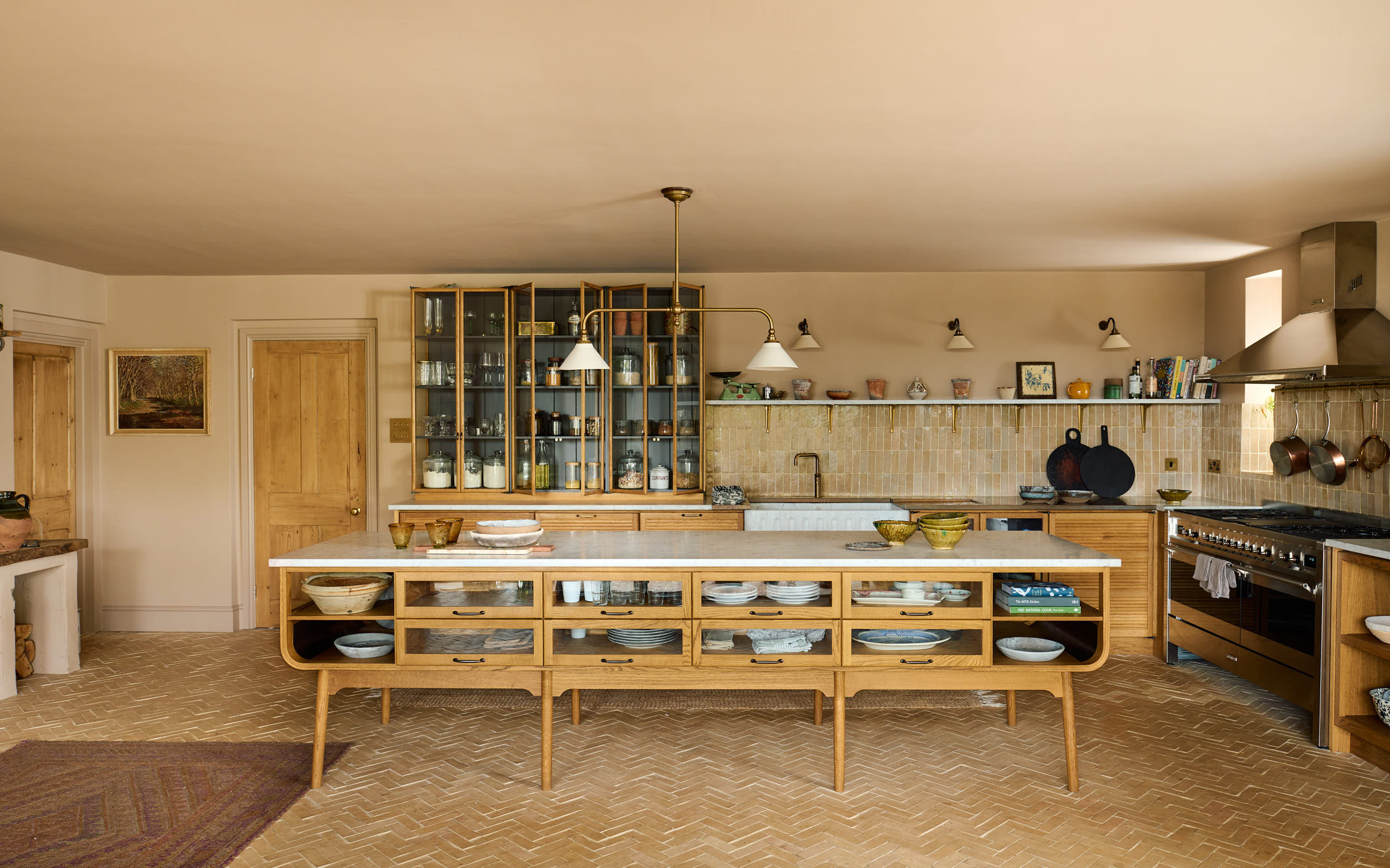 a kitchen with a large wooden kitchen island, herringbone brick flooring and wooden cabinetry