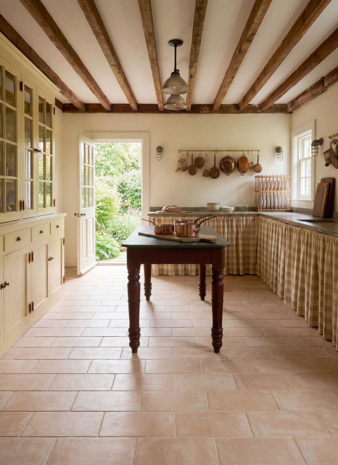 a country kitchen with stone flooring, yellow and white gingham skirt under the countertops and a large prep table in the middle