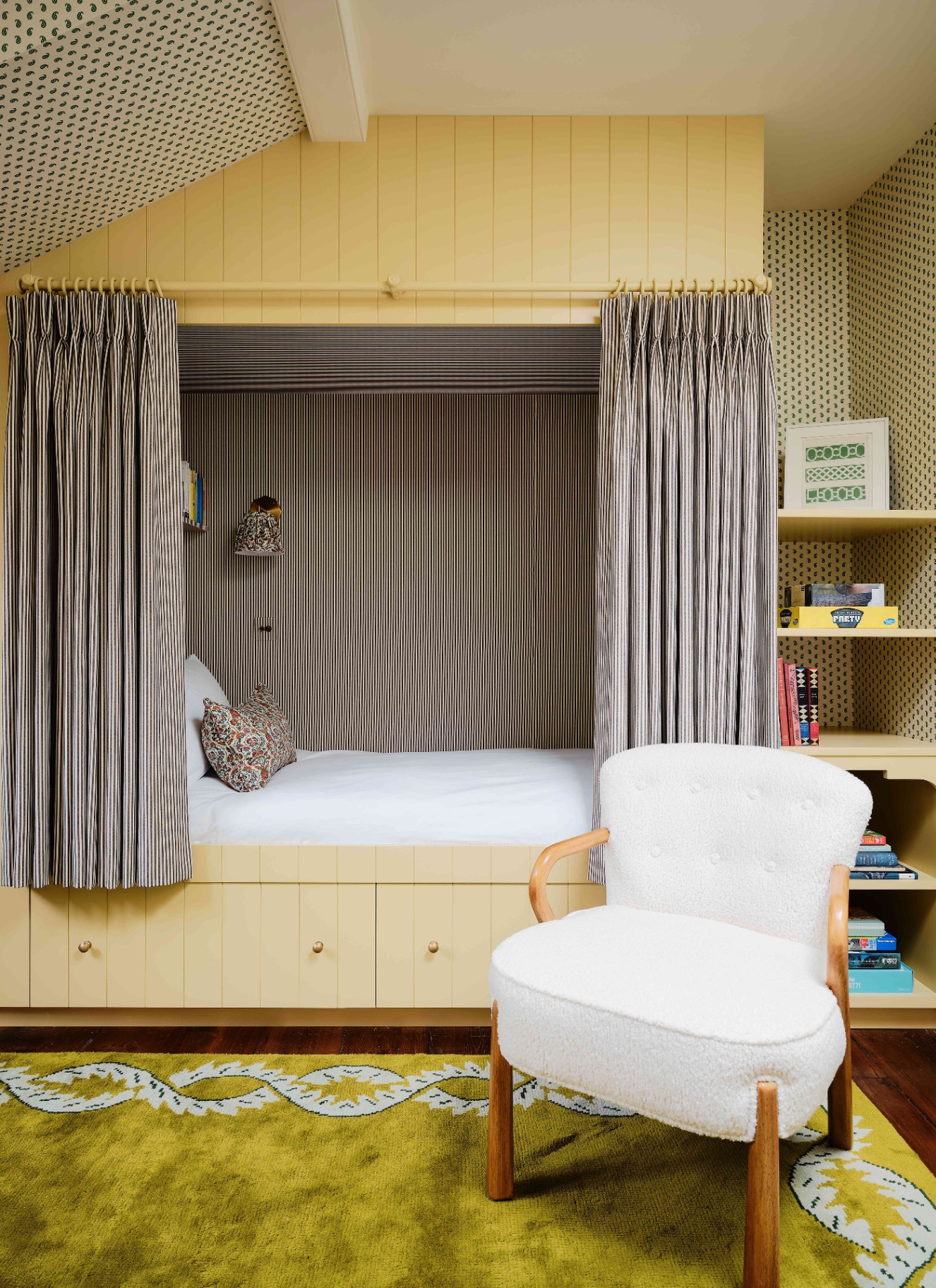 a childrens bedroom with a pale yellow painted bed nook cabin with black and white striped curtains