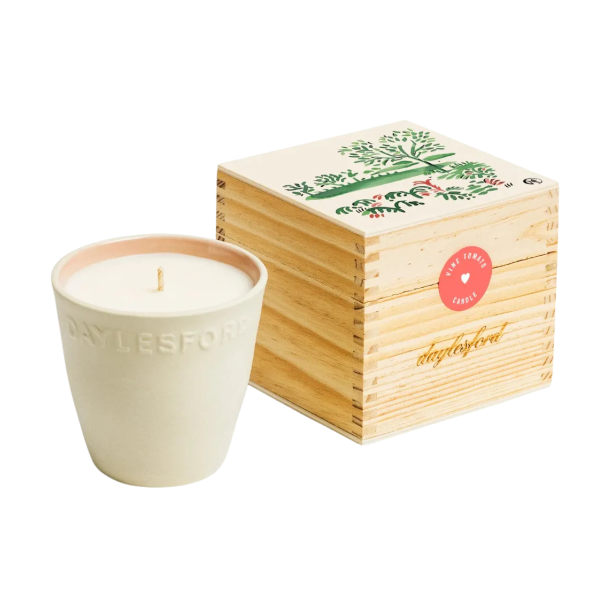 a white ceramic candle with the name daylesford on it next to a wooden box with a forest illustration on the lid