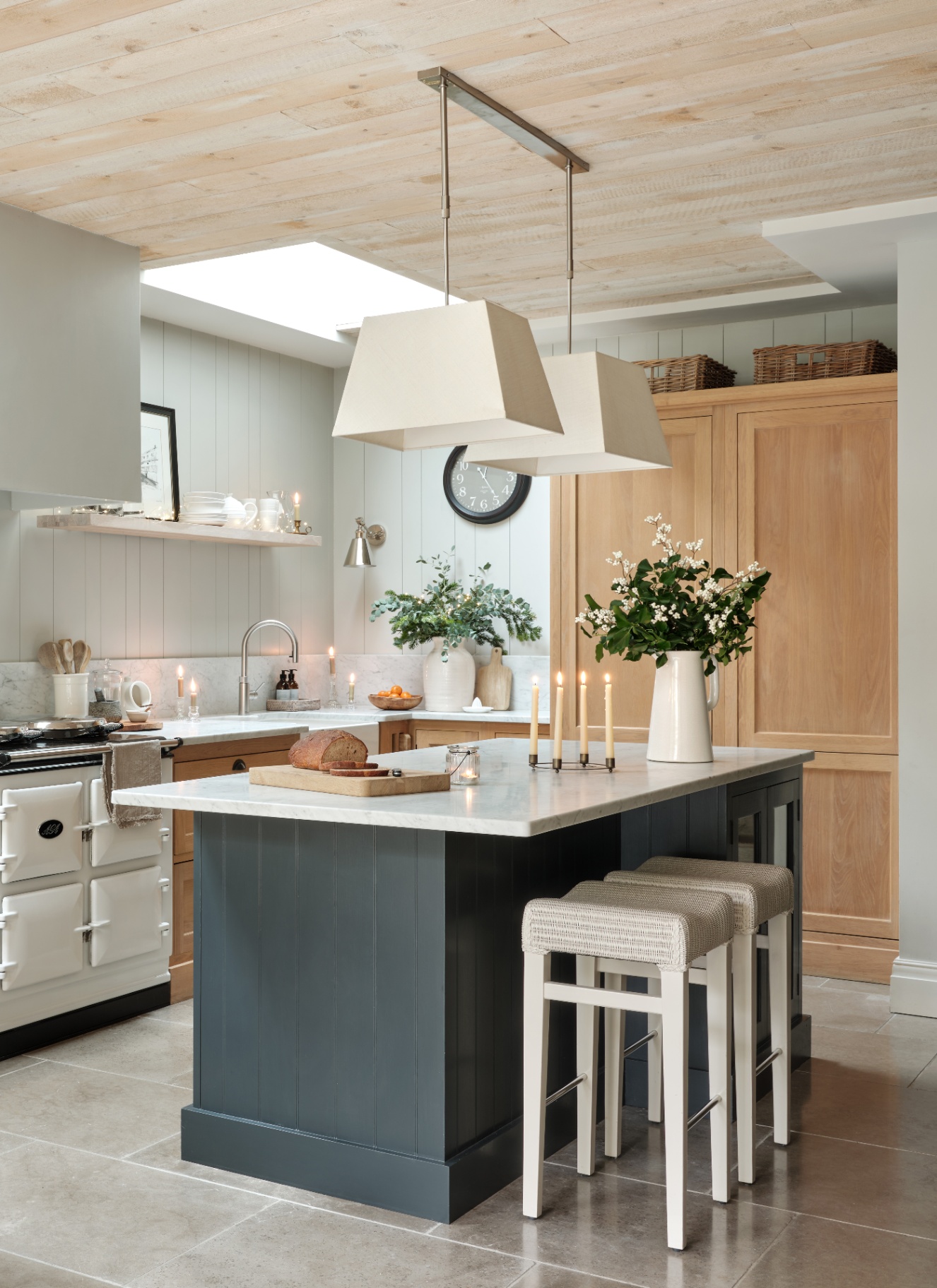 a kitchen with a navy kitchen island with white stalls, white walls and a large wooden freestanding cupboard