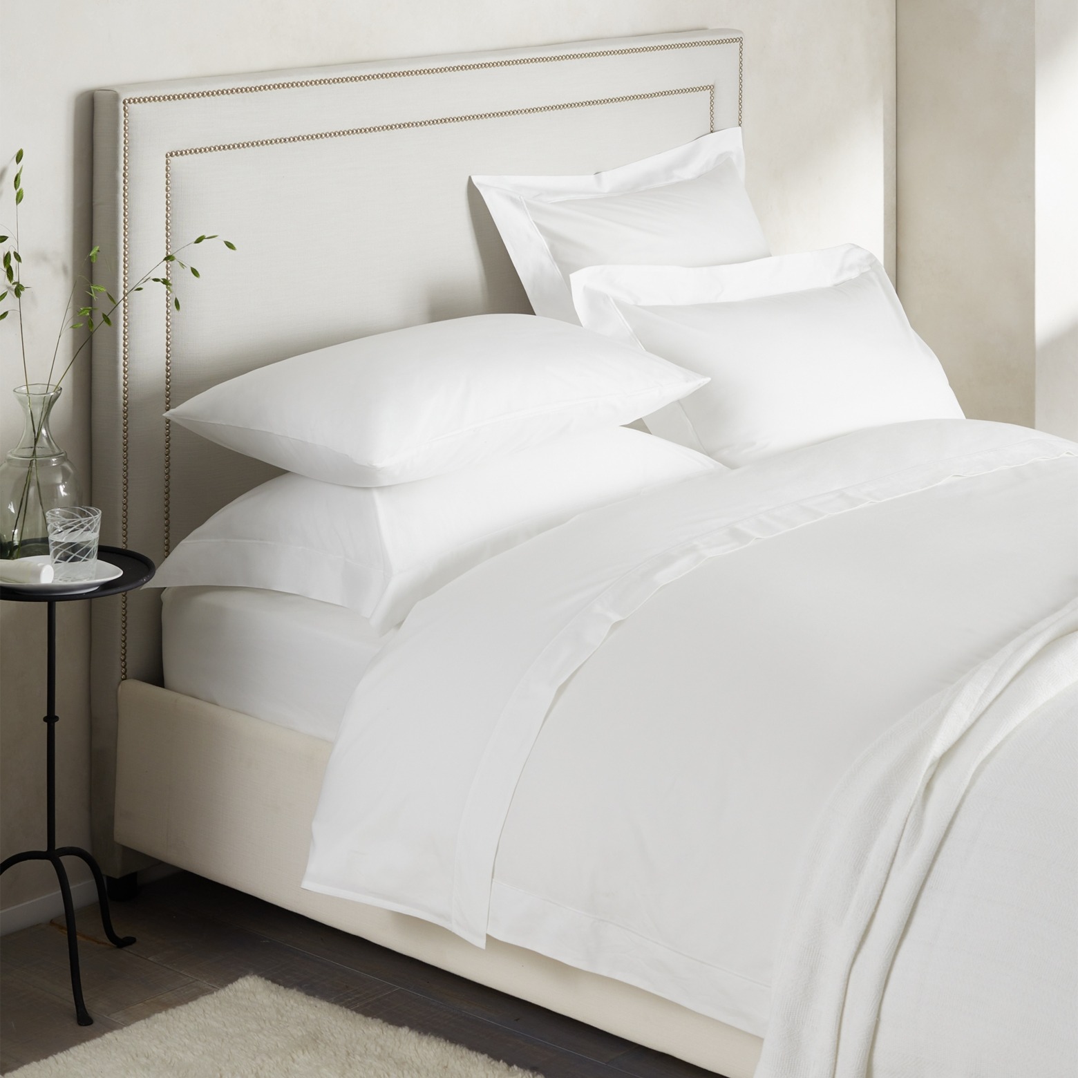 crisp white bedding set on a bed with a grey headboard