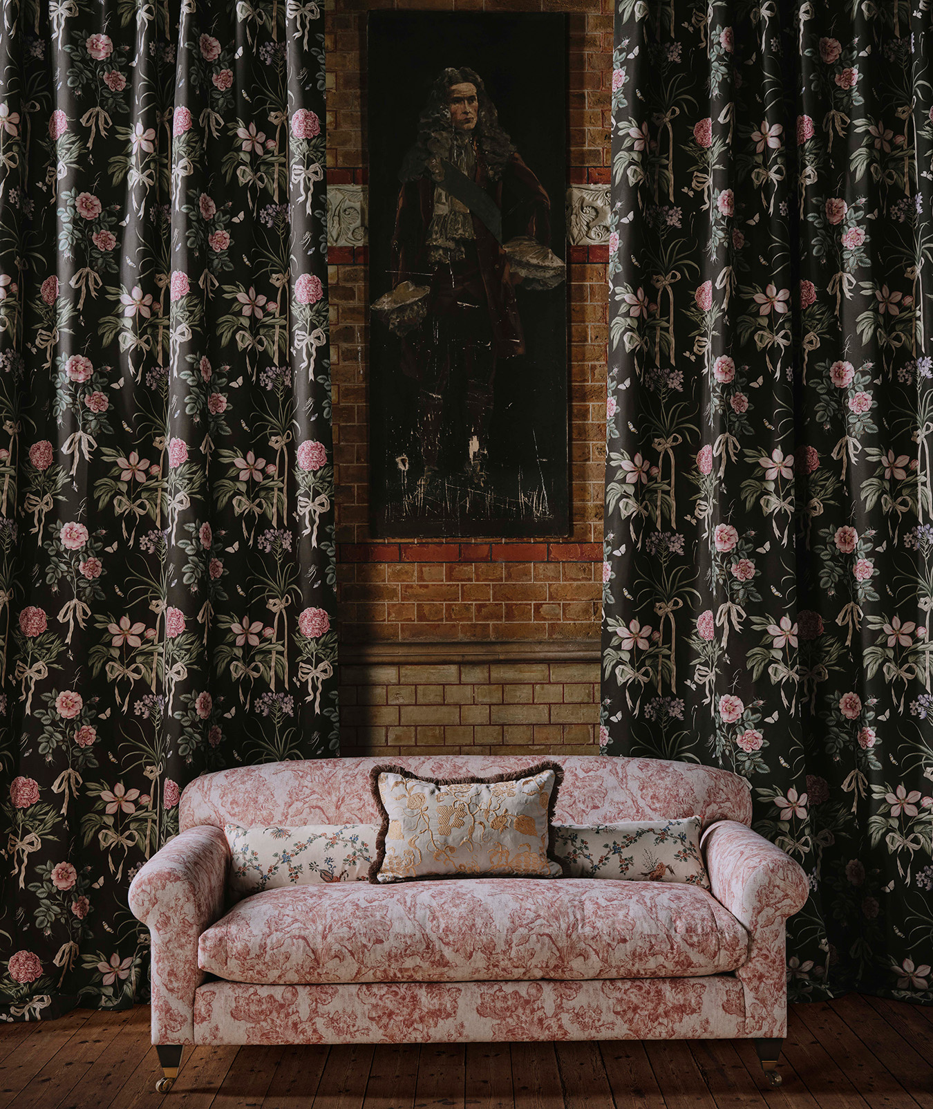 a room with a floral sofa and floral wallpaper and a portrait of a man