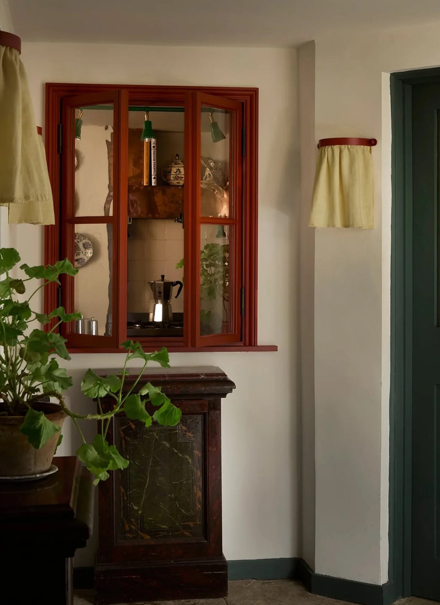 a kitchen corner with a red painted window opening up to show a silver italian coffee maker