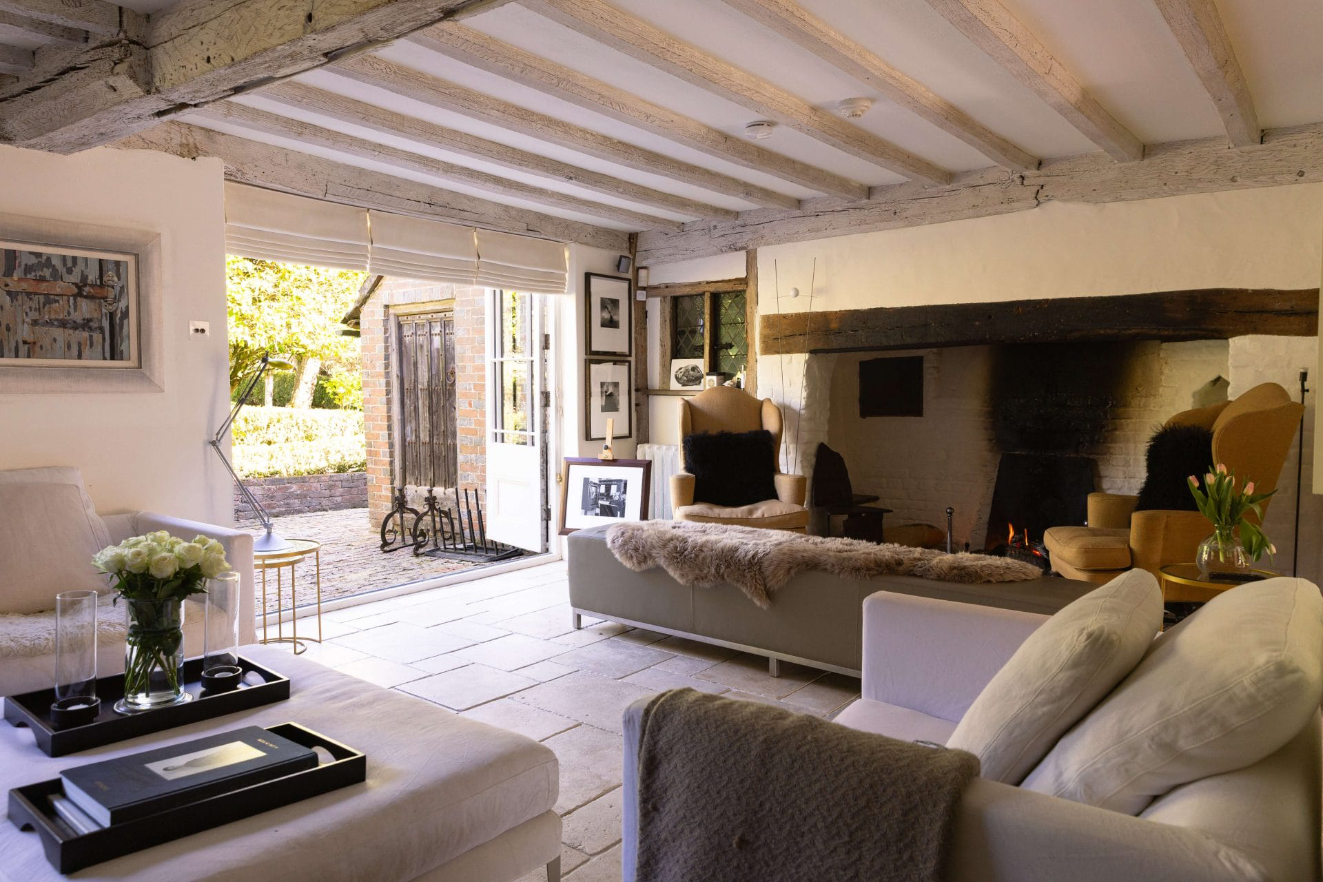 A cottage living room with wooden beams, a large fire place and cream sofas, former home of Princess Margaret