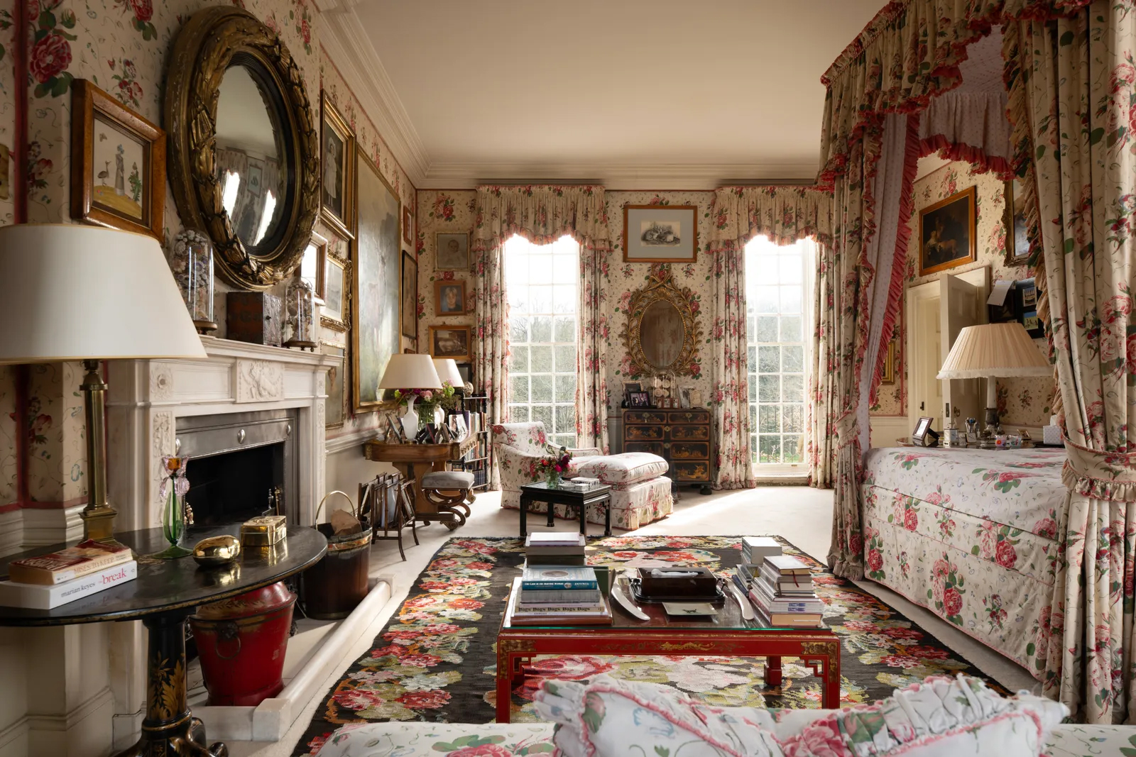 the principal bedroom at Ormeley Lodge, Richmond, covered with white and pink florals, a four poster bed and a large fireplace