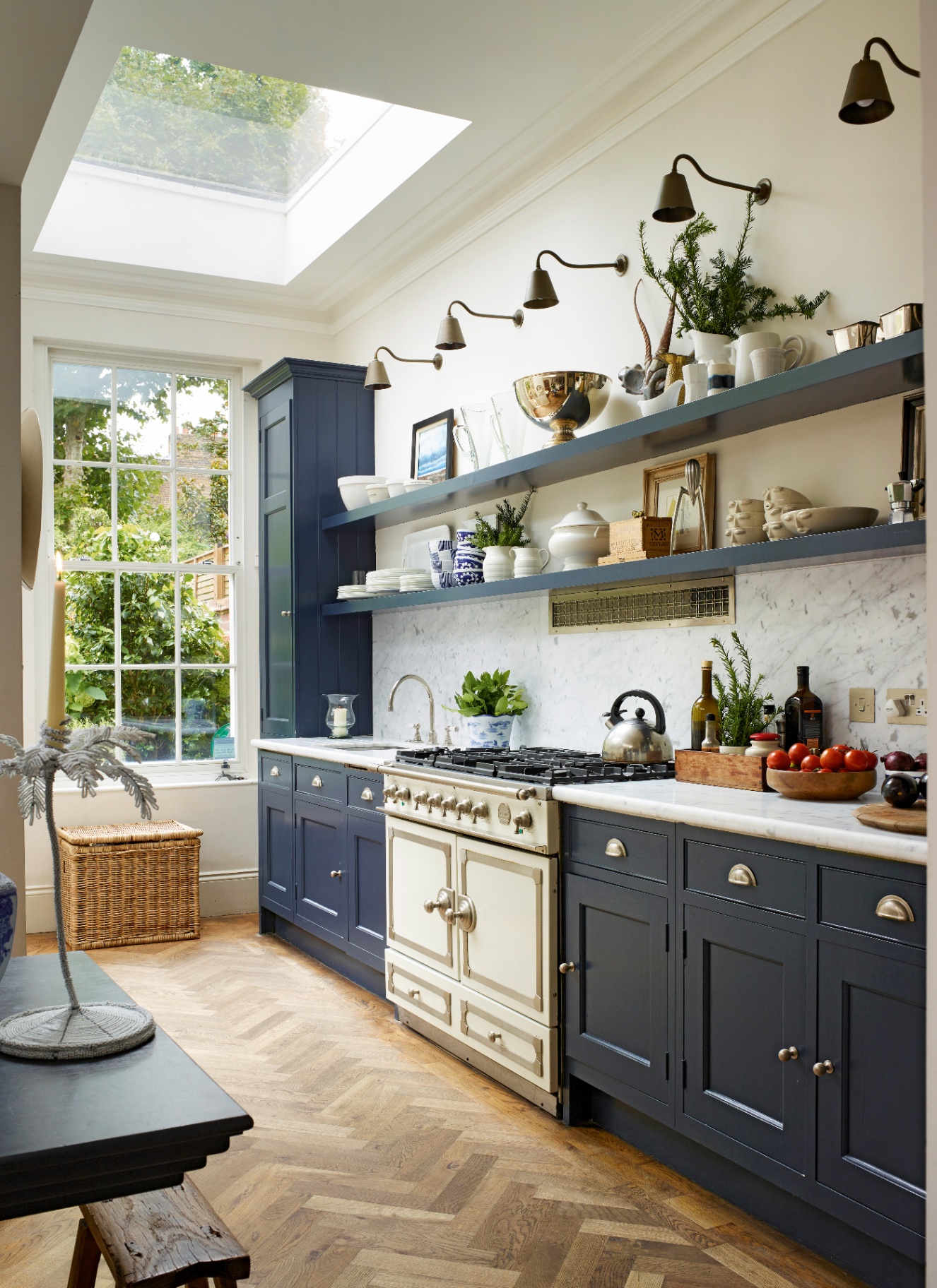 a narrow kitchen with navy cabinets, a white range cooker, high ceilings, a sky light and navy open shelving