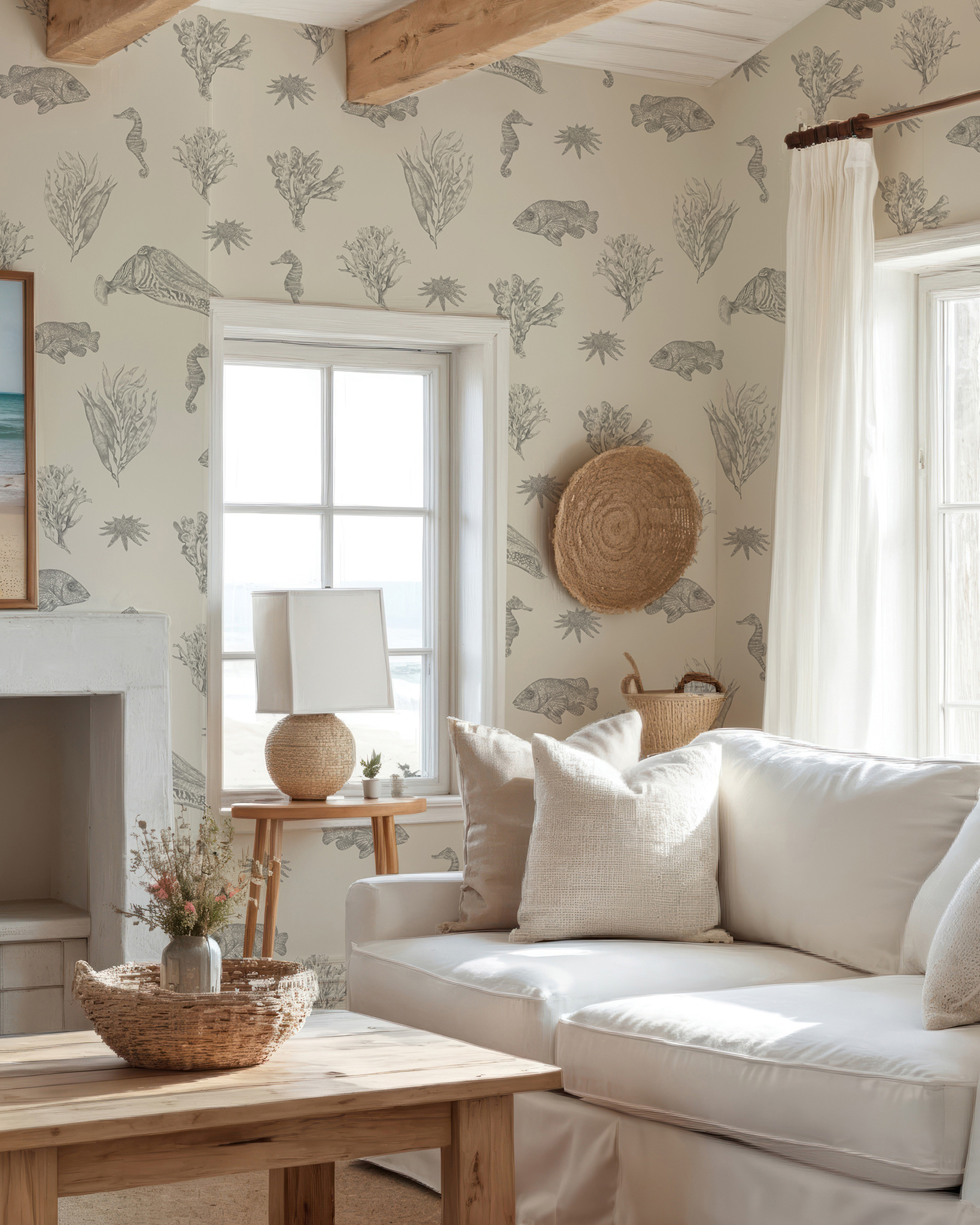 a living room with a cream and grey wallpaper featuring different sea creatures, a white linen sofa, a wooden coffee table with a rattan bowl and a rattan plate on the wall