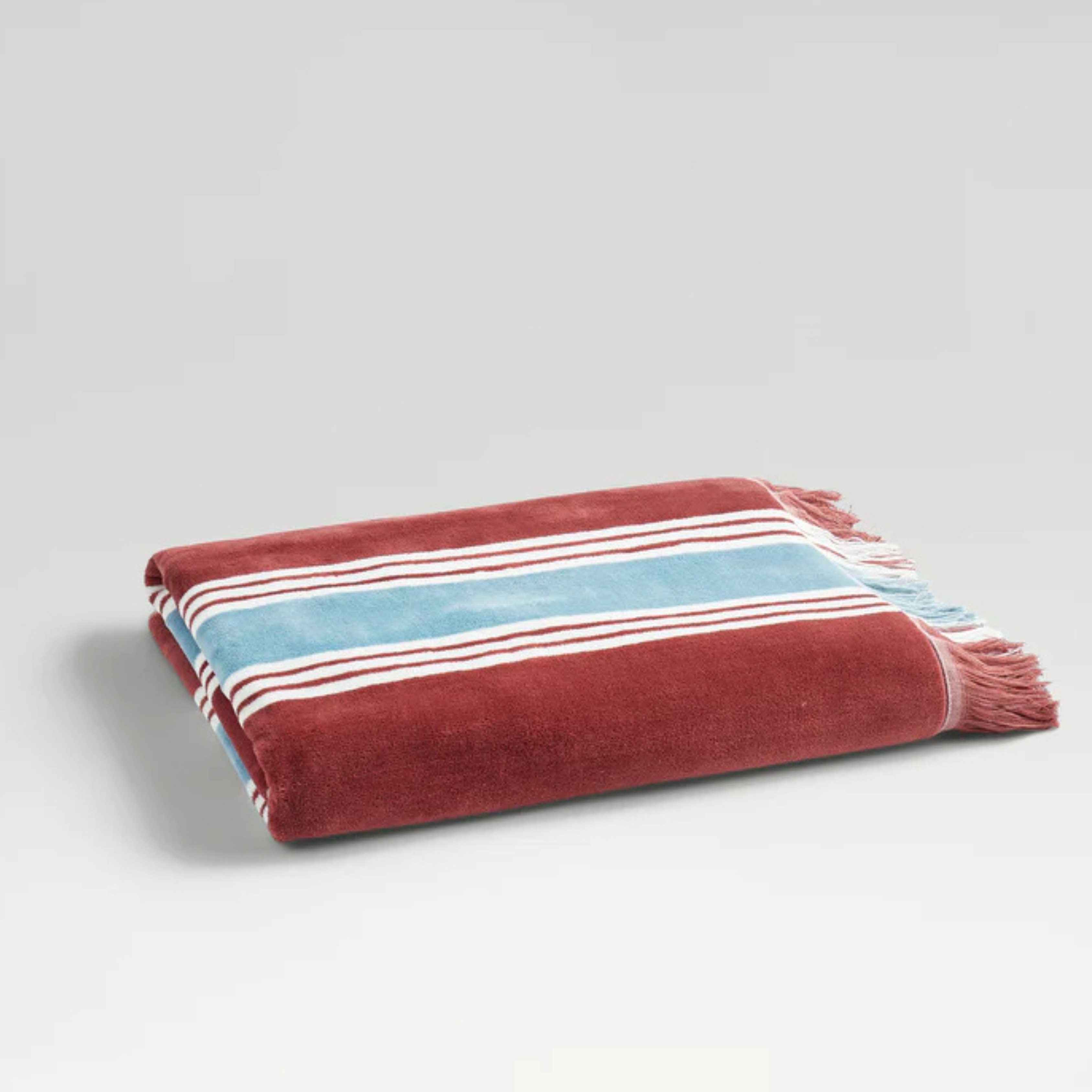 Christys College Beach Towel pictured with striped and fringe detailing folded with a grey background