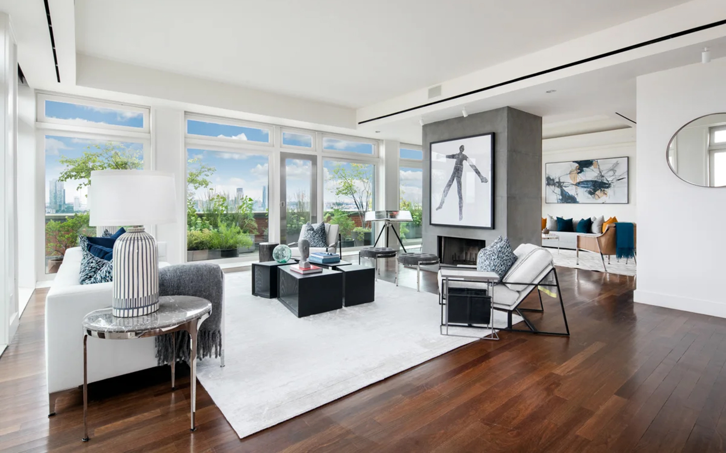 meryl streep's tribeca penthouse, an image of the living room with dark wood floors, a large white rug and modern furniture looking out to the city