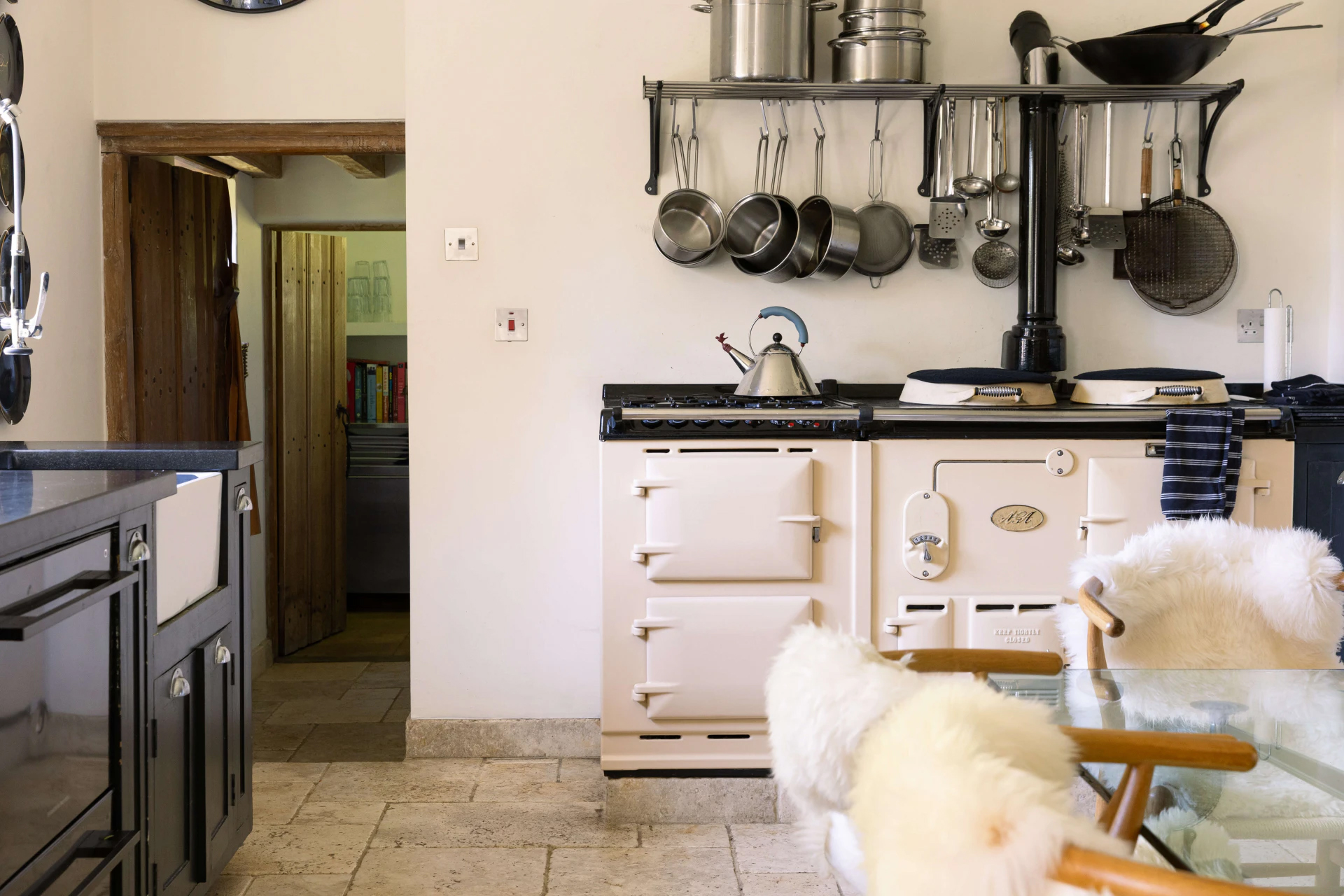 a country kitchen with a large cream aga and silver saucepans hanging above it, former home of Princess Margaret