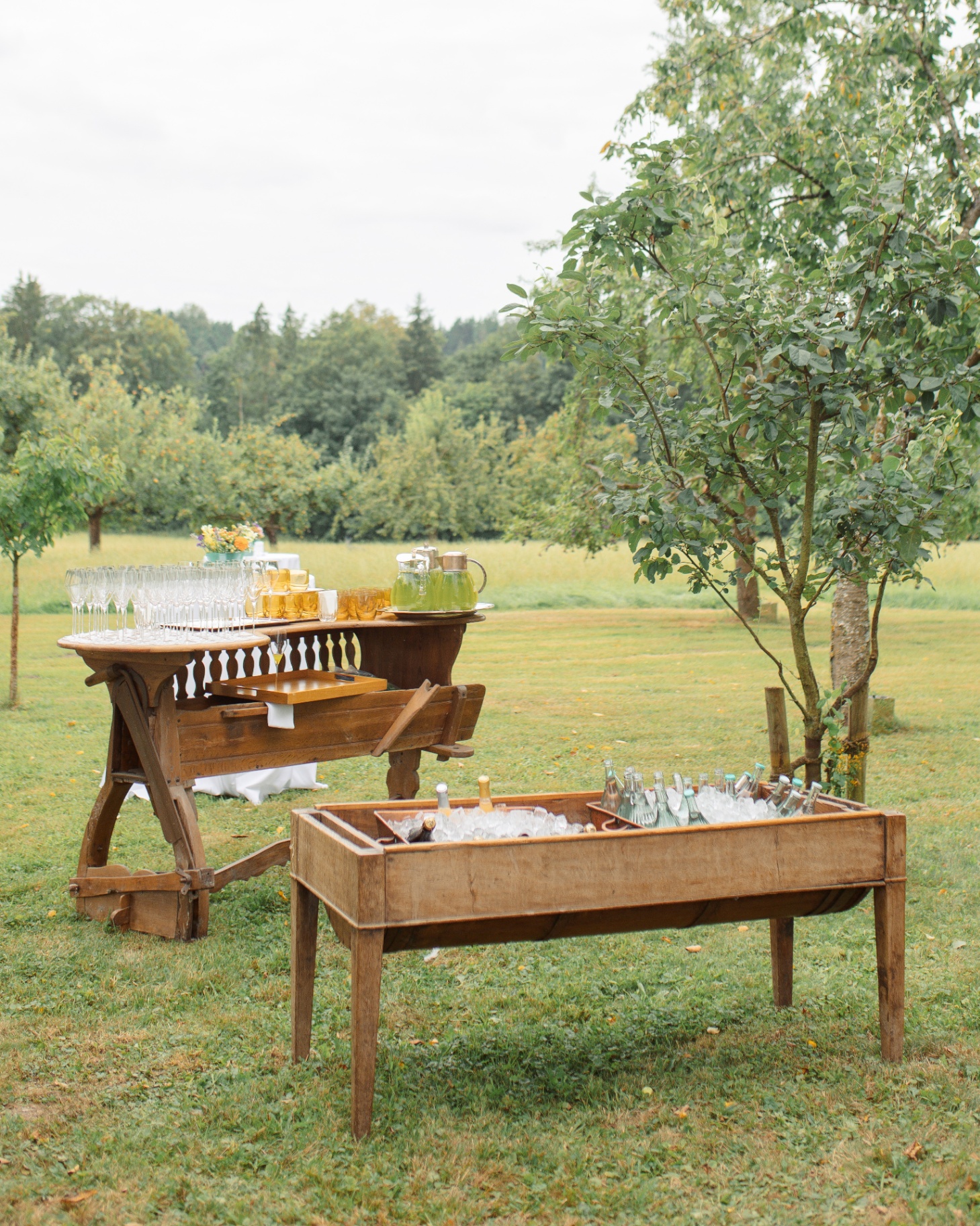 an outdoor large wooden trough filled wtih ice and champagne bottles