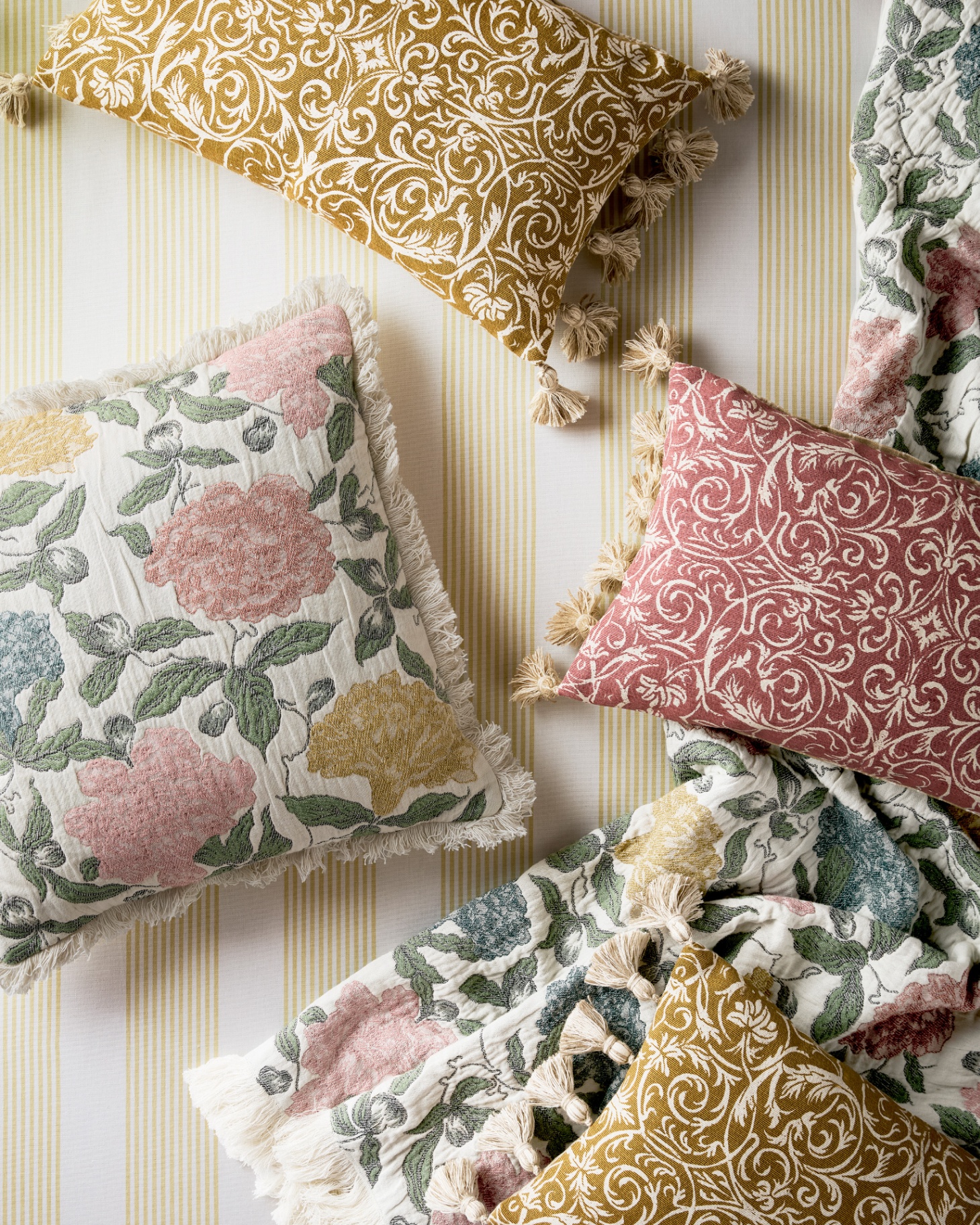 a few floral cushions laid on yellow and white bedding