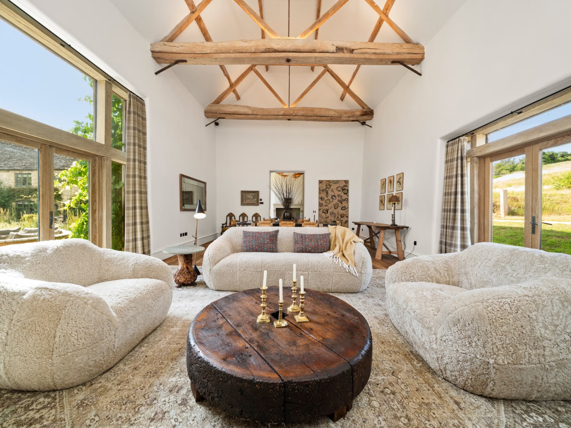 the living room of Kitesbridge Farm, Ellen Degeneres home in the cotswolds, with exposed beams, two large boucle sofas and a dark wood round coffee table