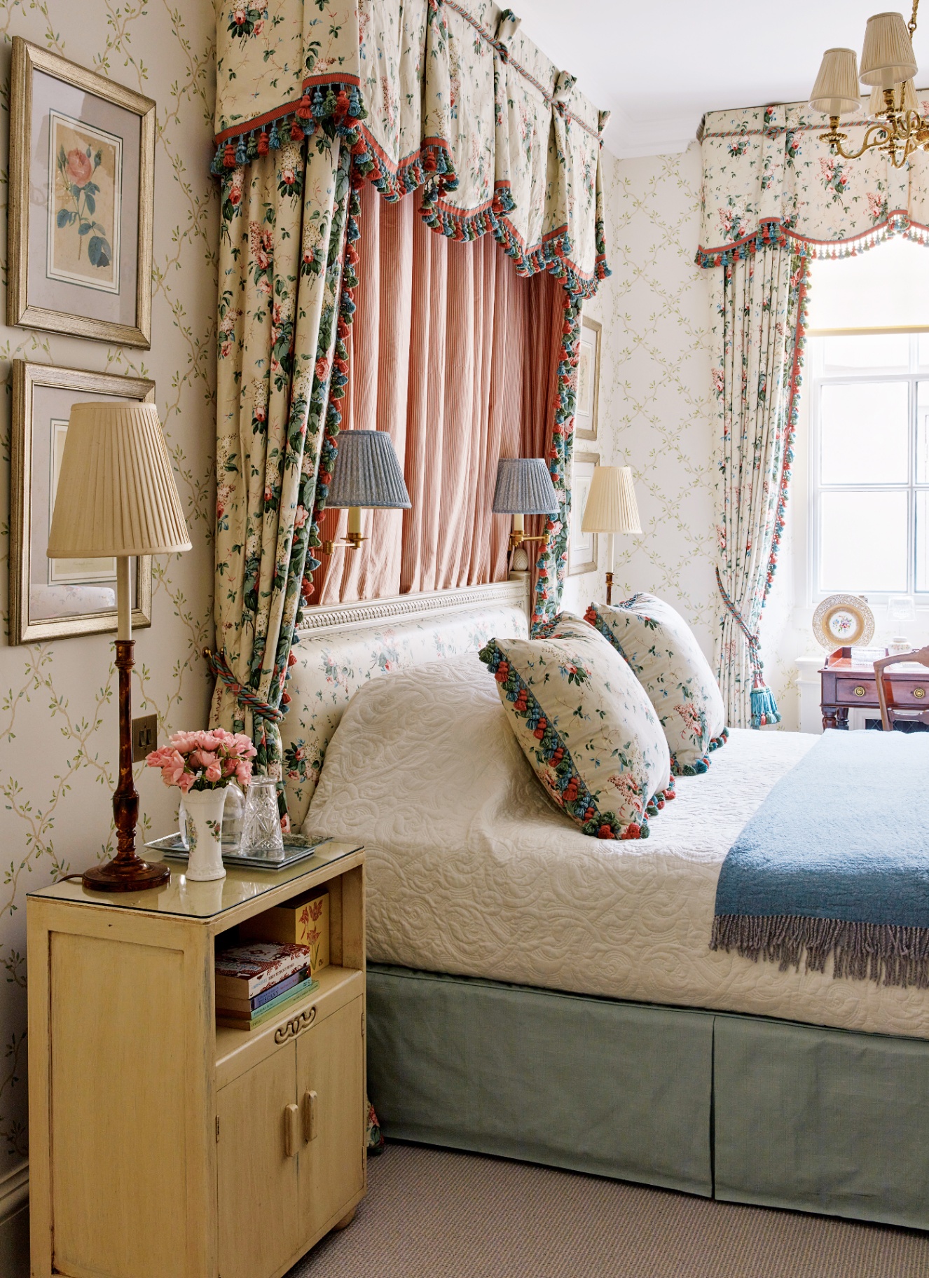 An elegant traditional bedroom featuring a grand fabric bed canopy with twin wall sconces mounted inside against pink pleated fabric