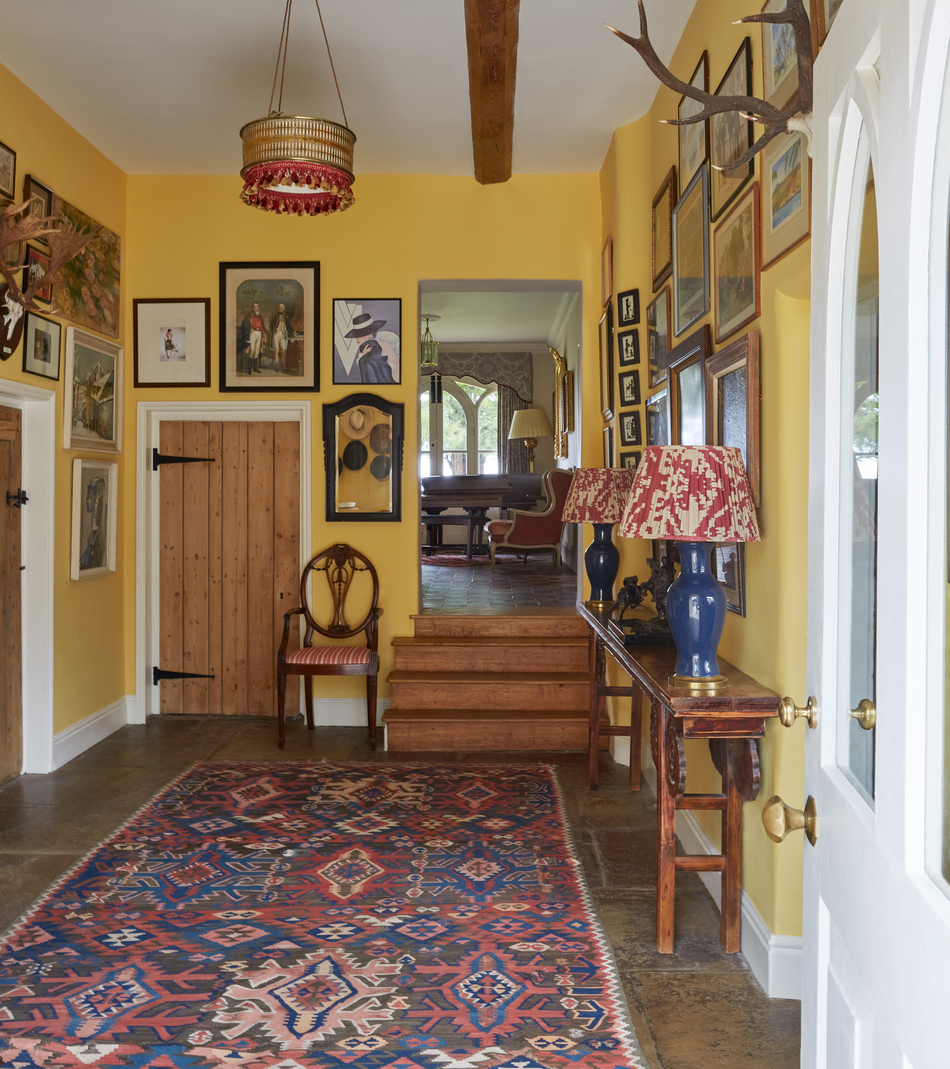 a traditional hallway with mustard yellow walls filled with art
