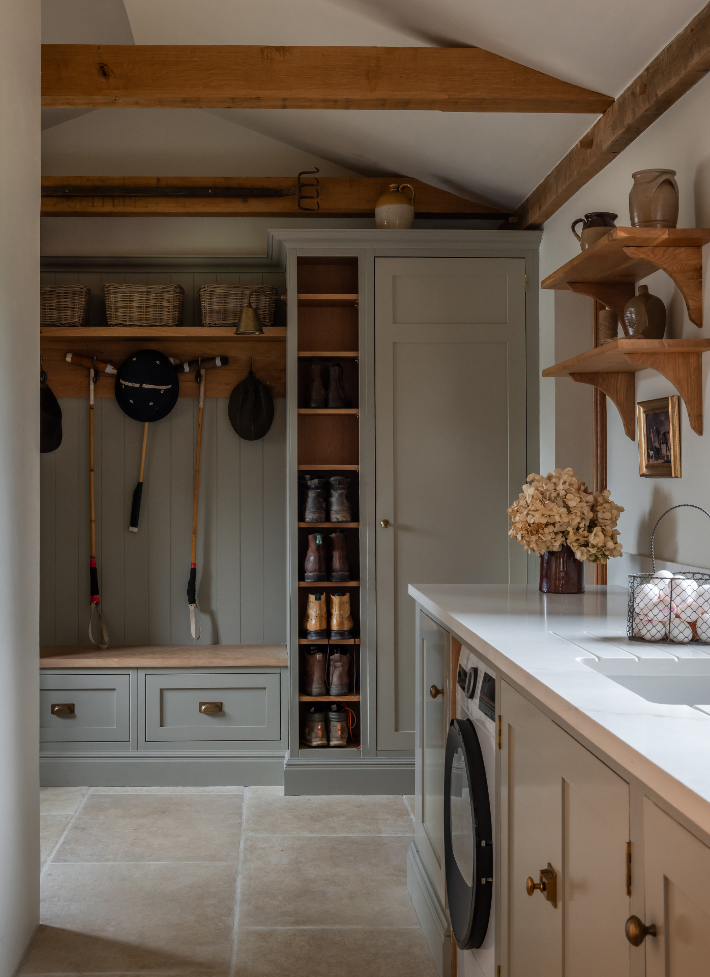 a boot room and utility room with green grey cabinetry, open shoe shelves and sport equipment hanging from hooks