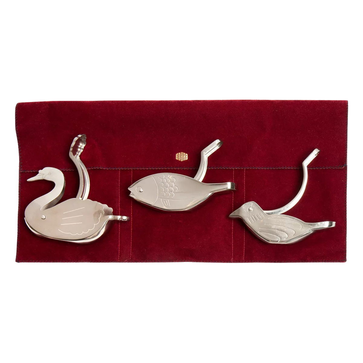 a set of 3 silver lemon squeezers in the shape of animals on a red velvet packaging