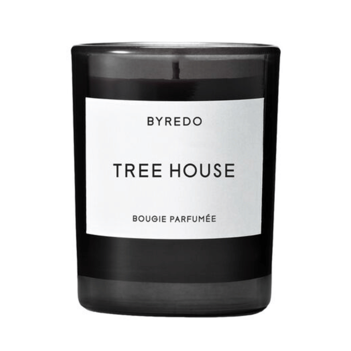a black glass candle with white wax and a white label that says tree house