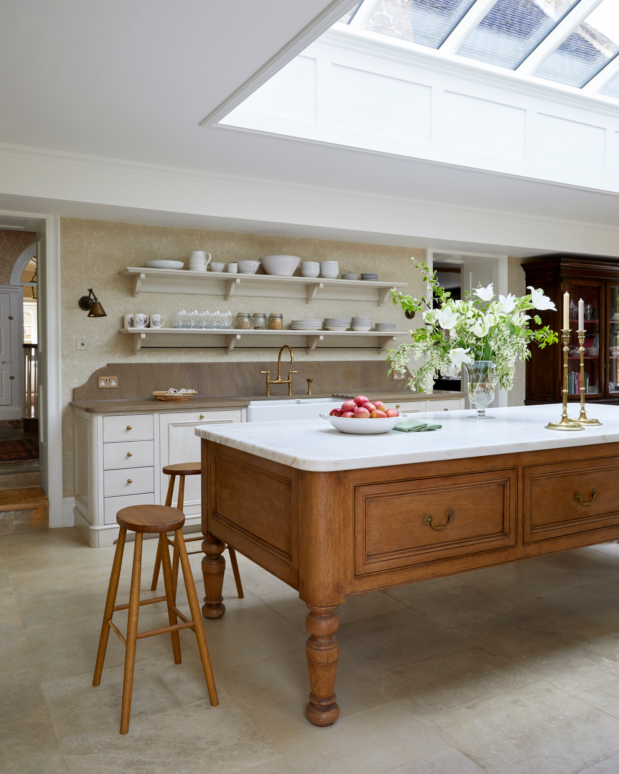 a kitchen with a large wooden island an a white marble top, white cabinetry with wooden countertops and a large skylight