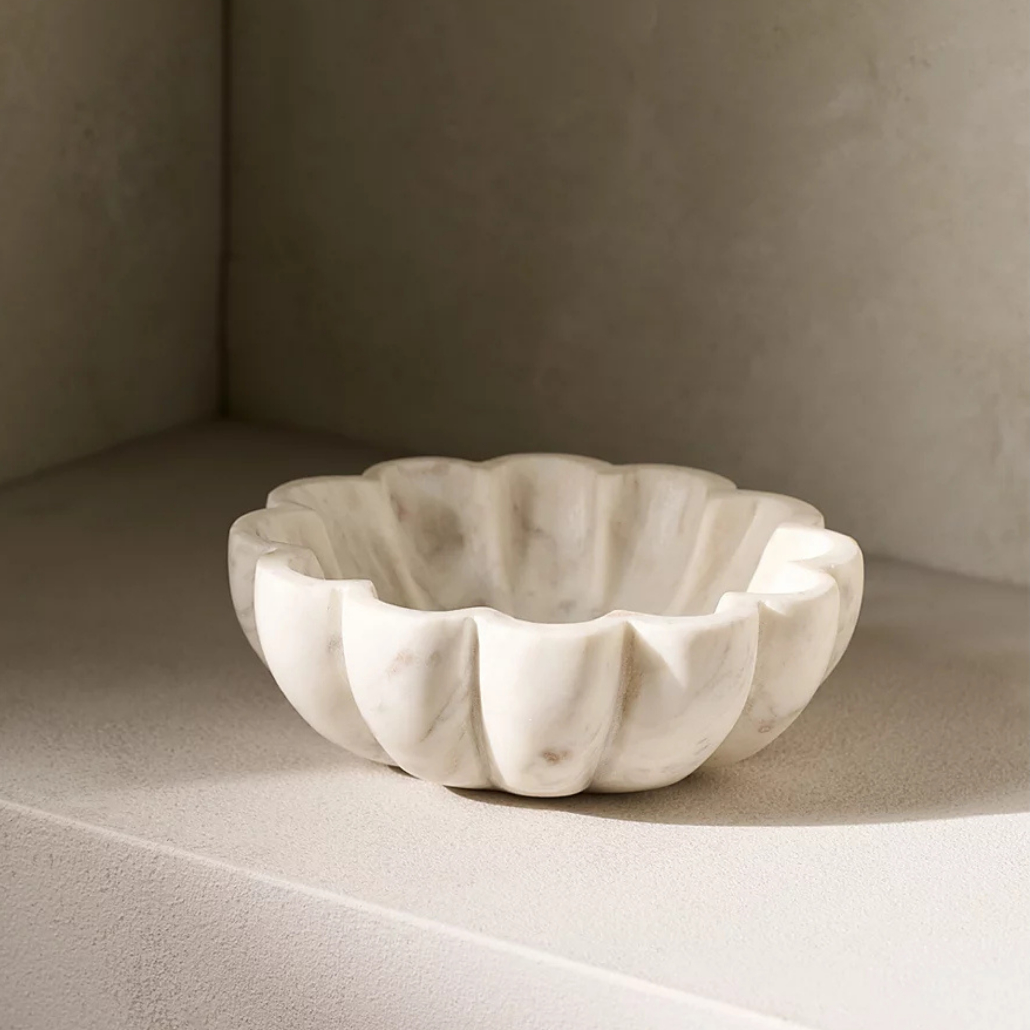 Larton Scalloped Marble Bowl from The White Company pictured on a shelf with shadows casting light